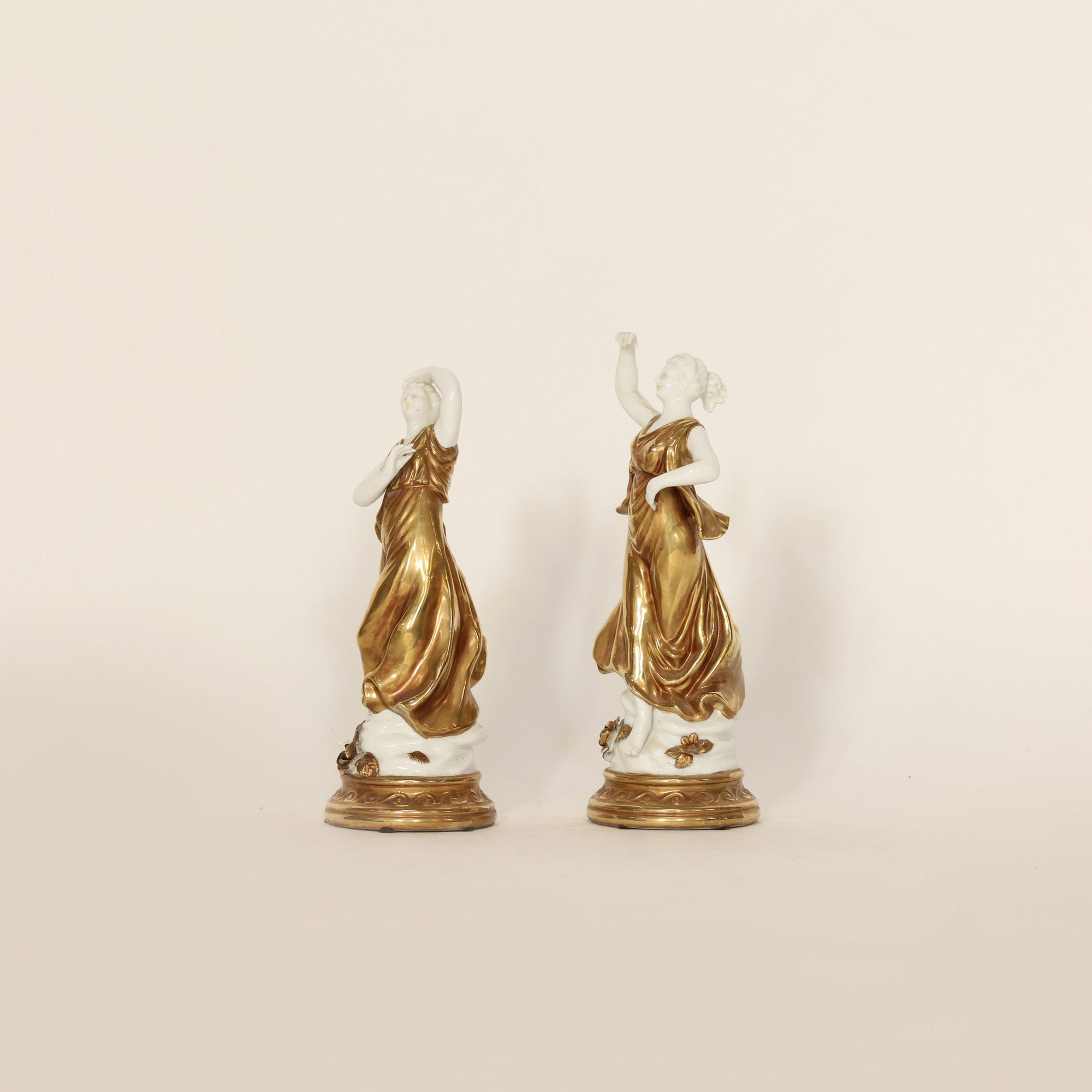 Two gold and white decorative figures on a beige background