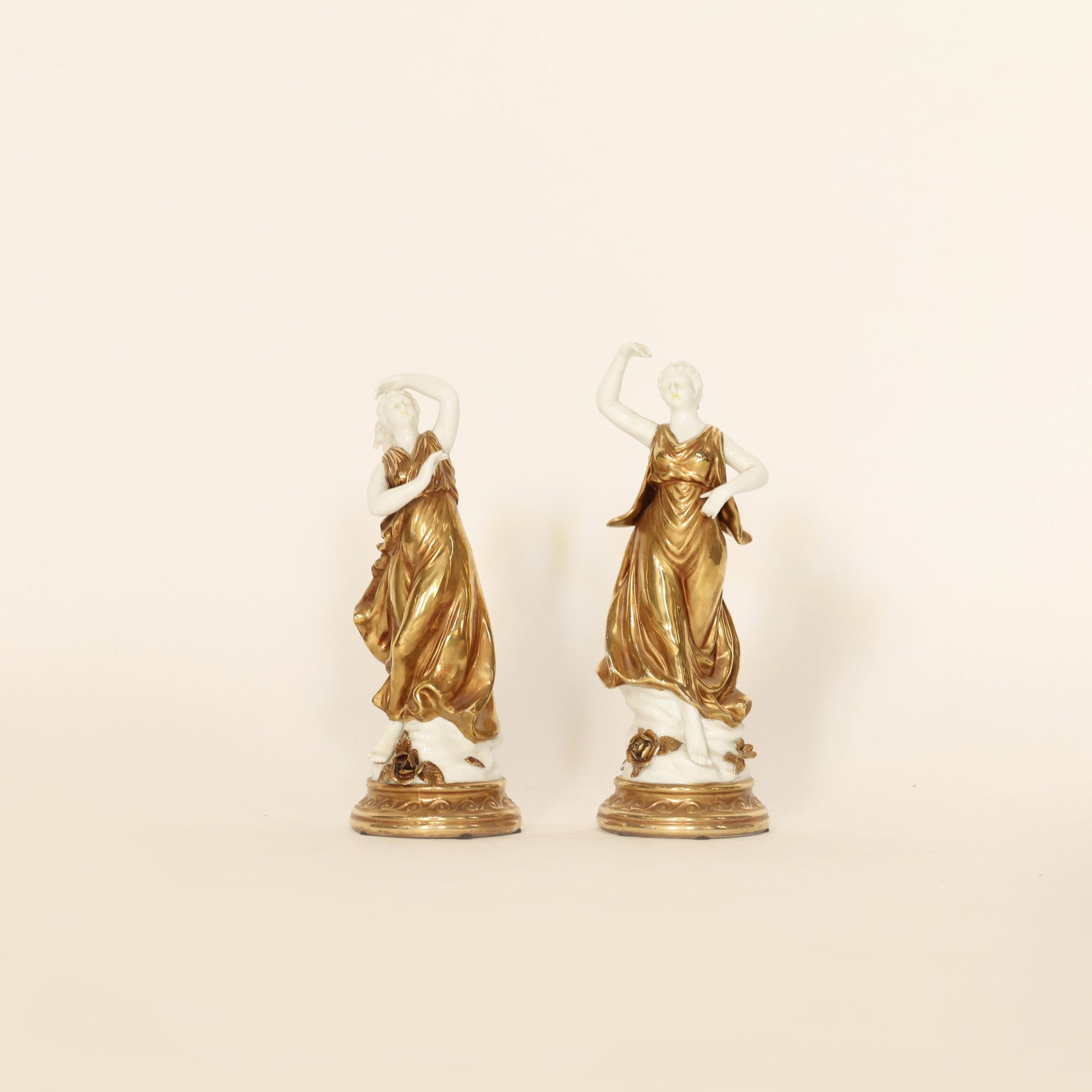 Two gold statues on a beige background