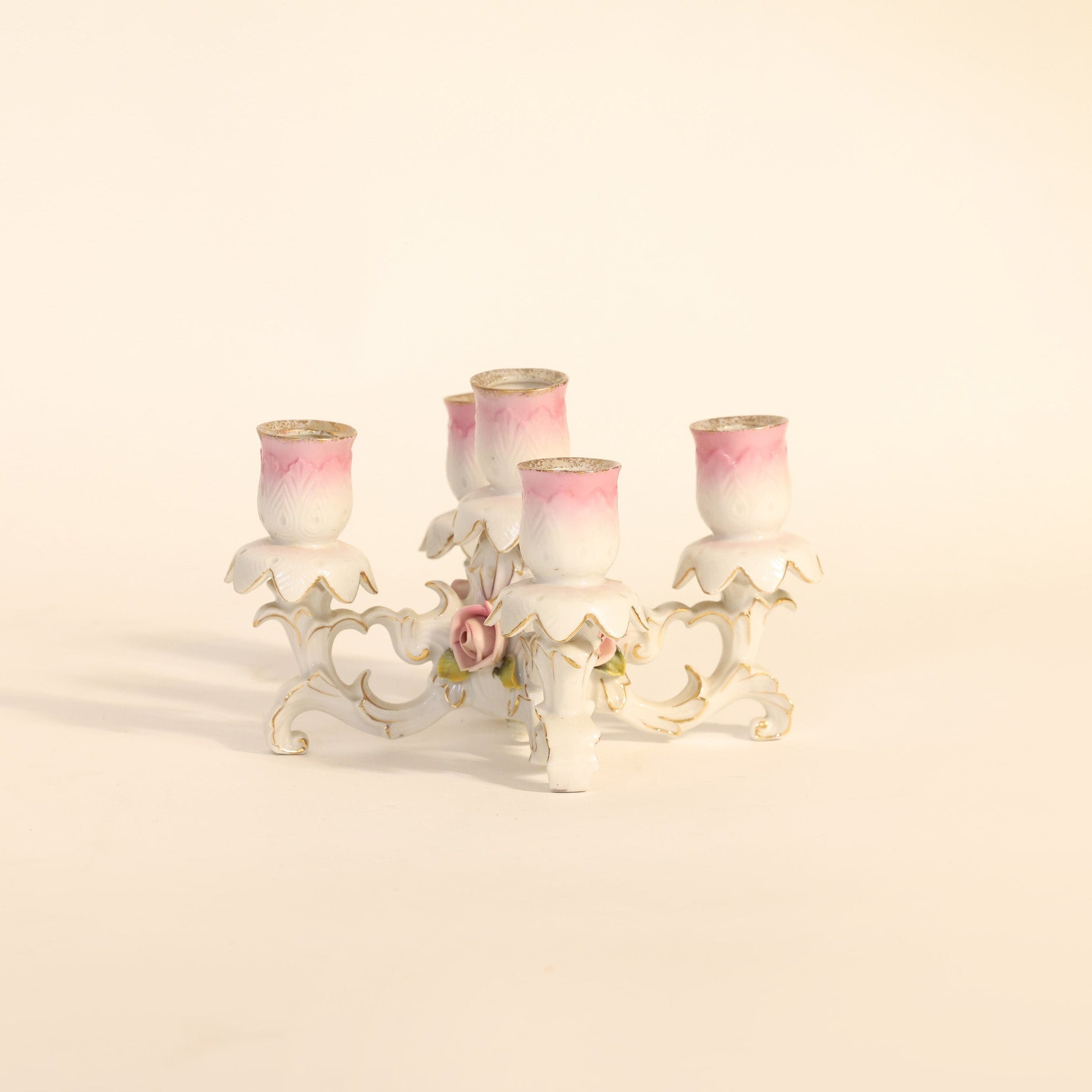 Decorative candle holder with four pink candles on a beige background