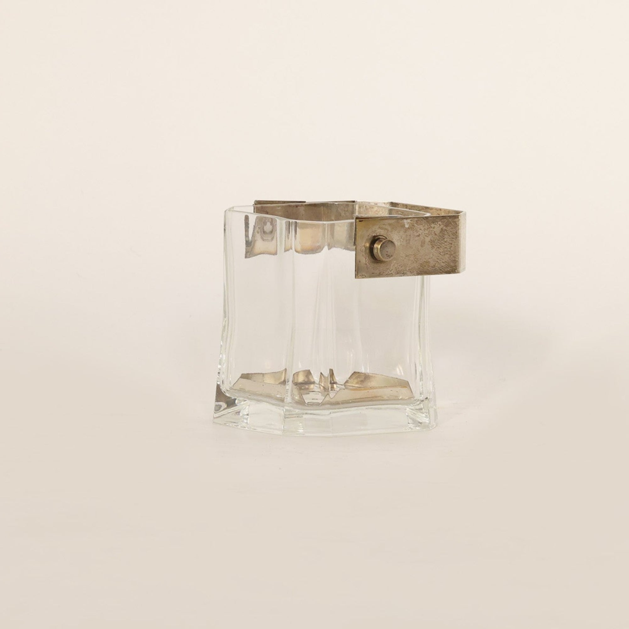 Clear vintage vessel composed of crystal and brass on beige background 