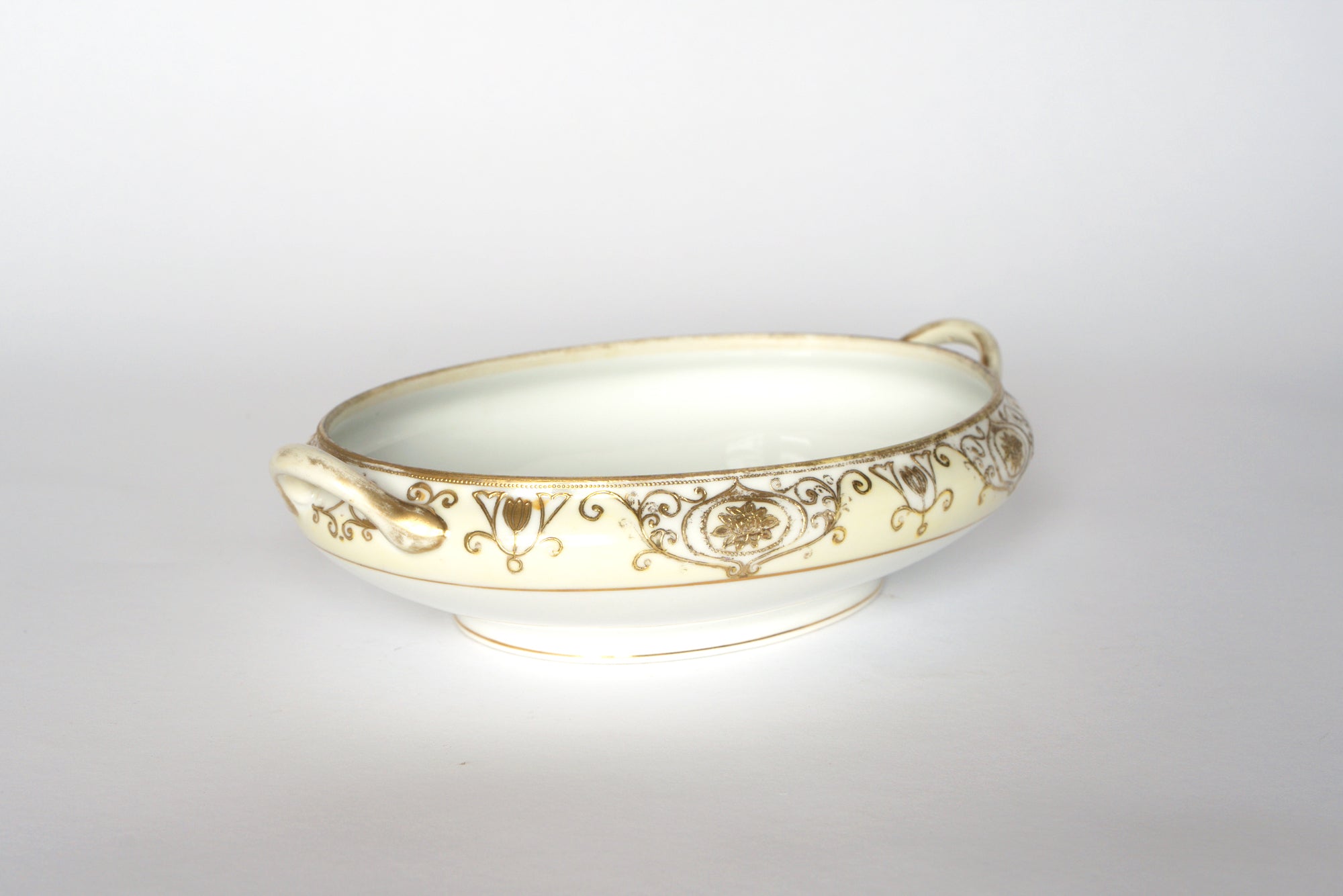 Set of two ornate, oval-shaped cream serving bowls from Euro Trash's Noritake vintage porcelain collection, each with two handles and gold filigree on the rim, displayed against a plain white background.