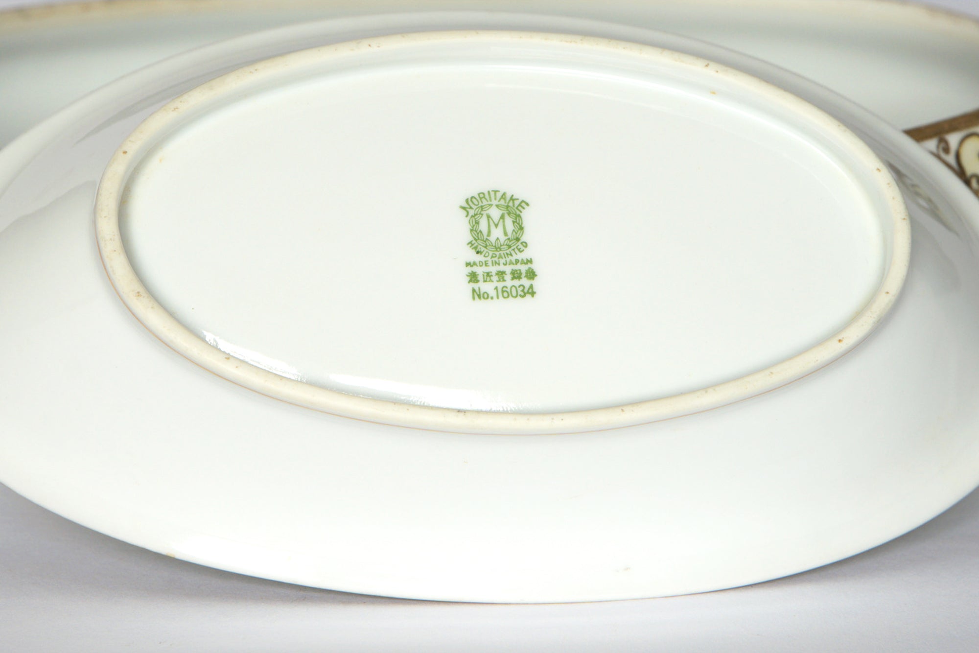 The underside of these Two Noritake Vintage Porcelain Serving Bowls by Euro Trash displays a green Morimura M mark, "Made in Japan," Japanese characters, and No.16034—perfect for collectors or to complement vintage china.