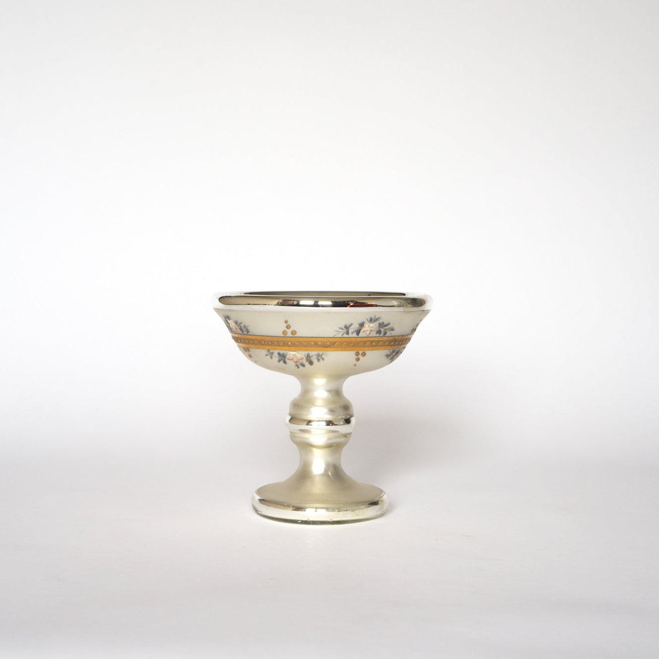 The Euro Trash Vintage Hand-Painted Mercury Glass Compote features floral details and gold accents on a cream-toned surface, displayed against a plain white background.