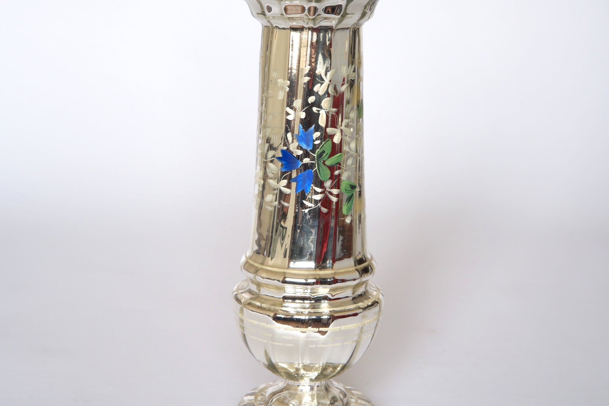 A pair of vintage silver mercury glass vases by Euro Trash, featuring engraved and hand-painted blue and green floral patterns, stand on round pedestals against a plain white background.