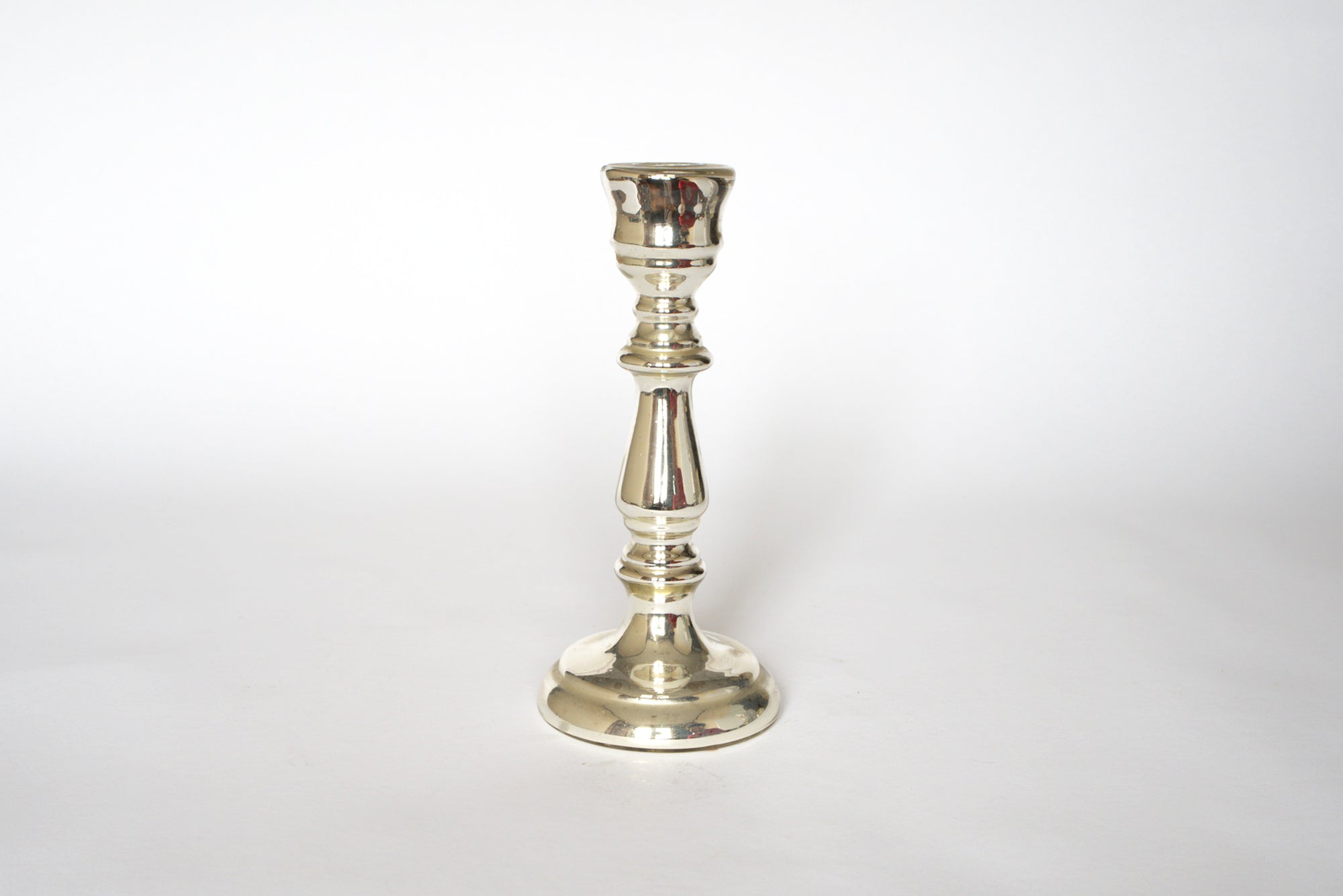 A pair of vintage mercury glass candleholders by Euro Trash, featuring round bases, slender decorative stems, and cups for candles, evoke classic elegance against a plain white background.