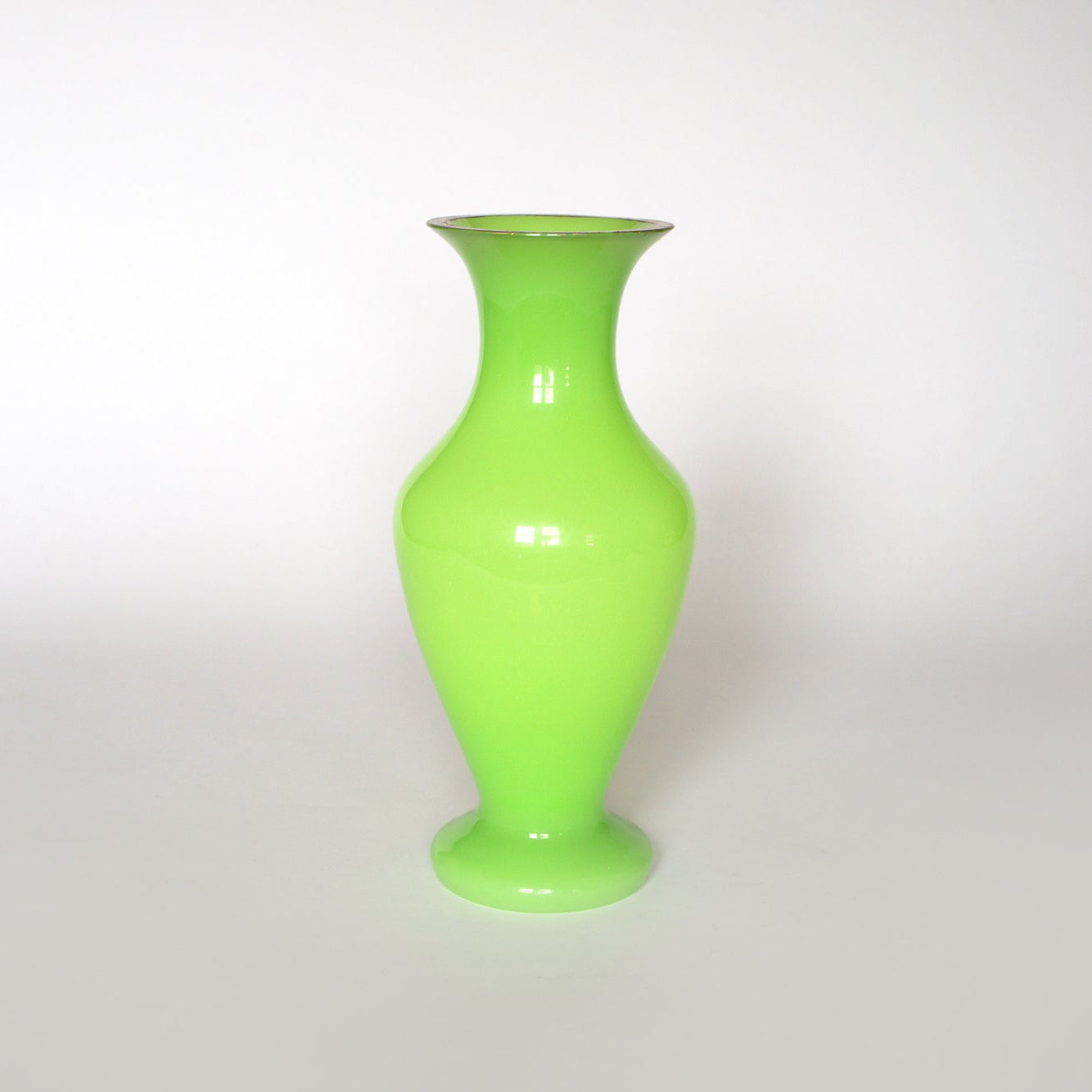 The Vintage Neon Green Opaline Glass Vase by Euro Trash, featuring a glossy finish and wide body with a narrow neck, stands out against a plain white background.