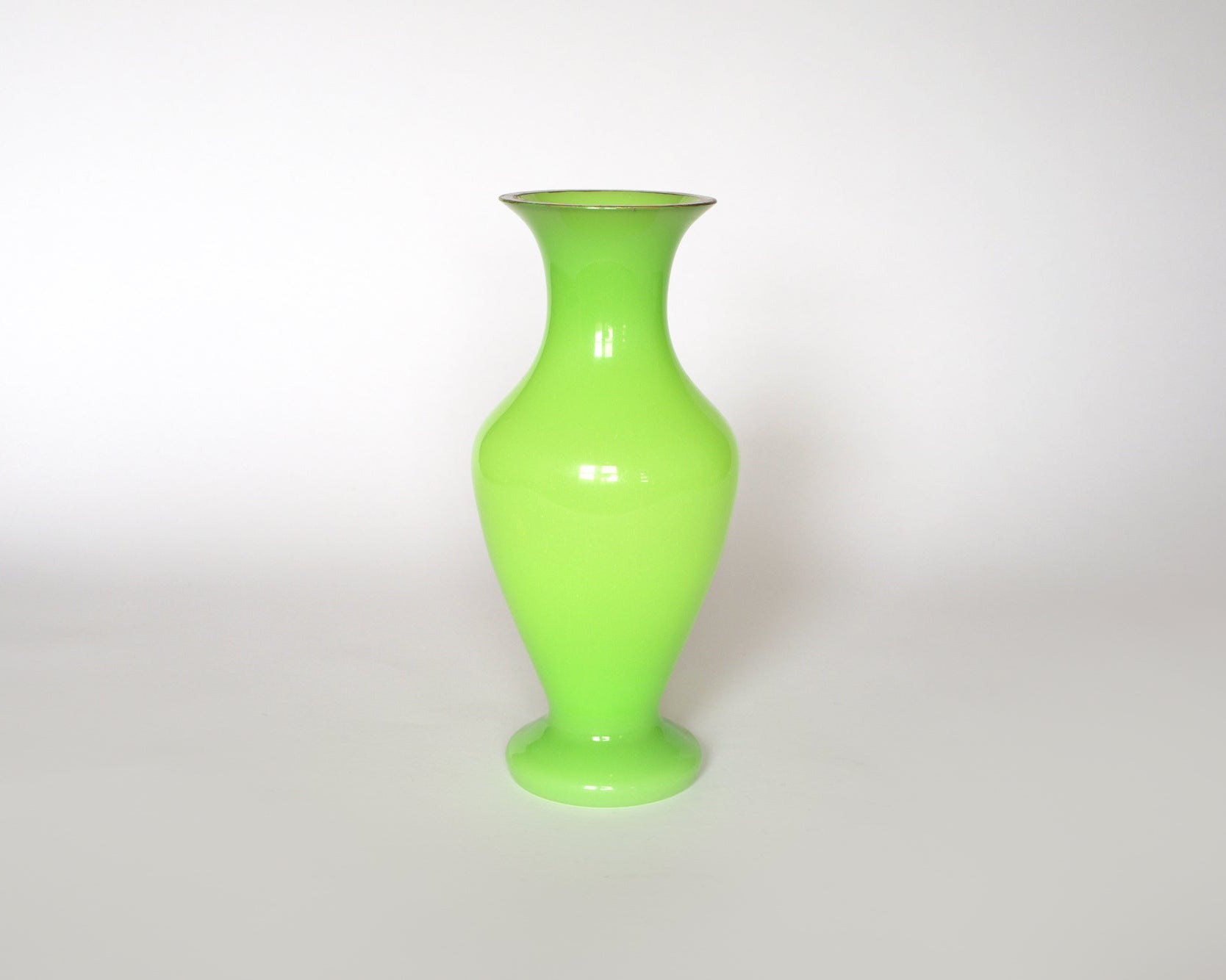 The Euro Trash Vintage Neon Green Opaline Glass Vase features a tall, glossy design with a narrow neck and wide body, adding vibrant style to any space on a plain white background.