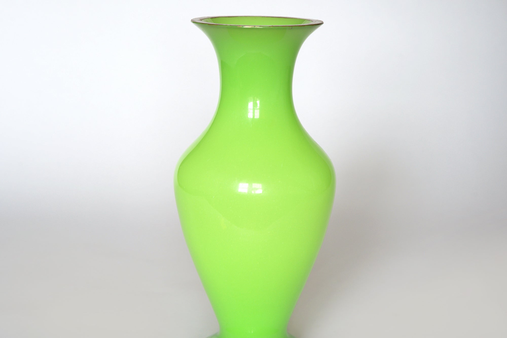 The Euro Trash Vintage Neon Green Opaline Glass Vase features a tall, glossy finish with a flared rim and narrow neck, showcased against a plain white background.