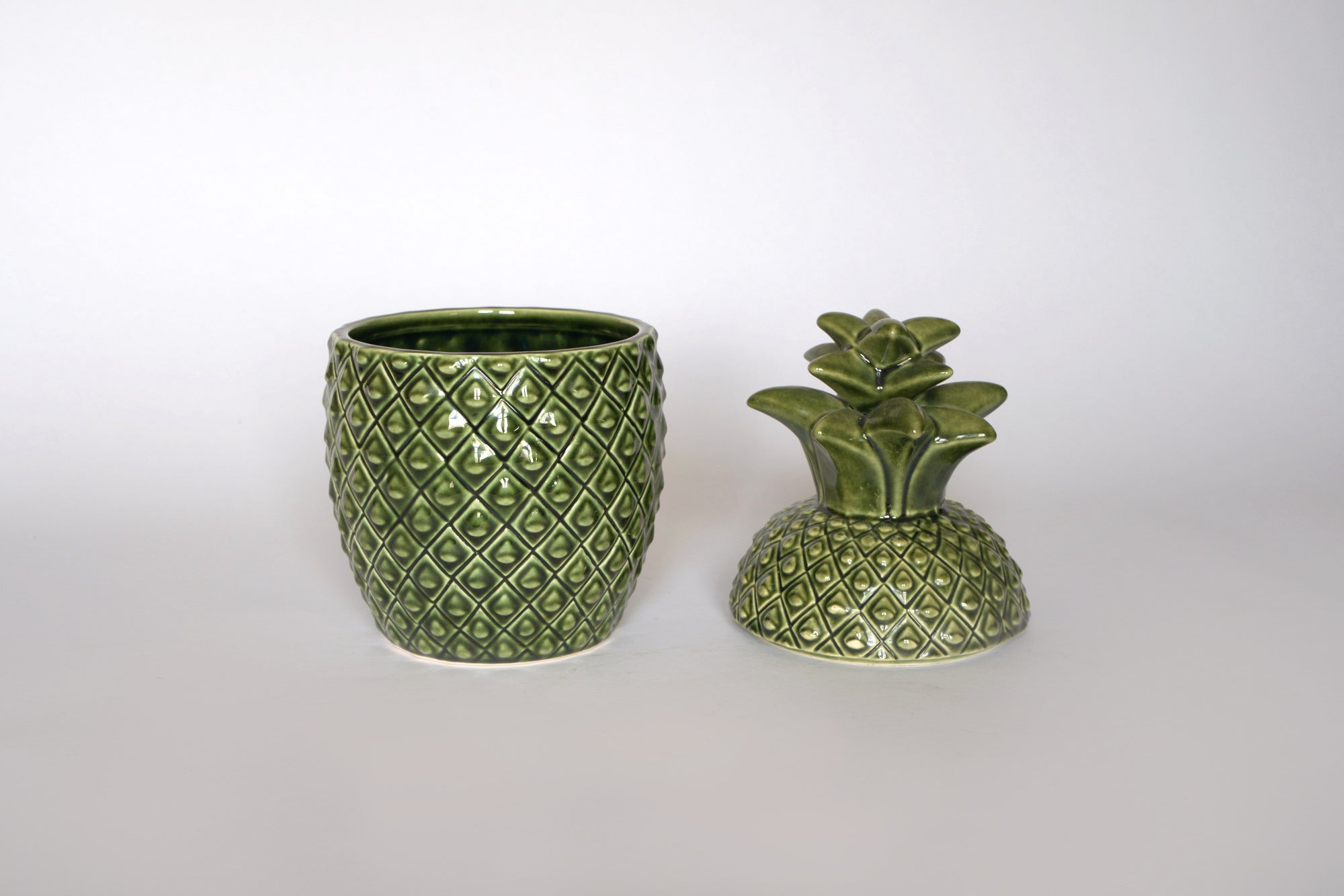 The Euro Trash Vintage Green Ceramic Pineapple Lidded Canister features a diamond pattern and a leafy lid, making it perfect for tropical kitchen decor or as a unique storage jar, shown here against a plain white background.