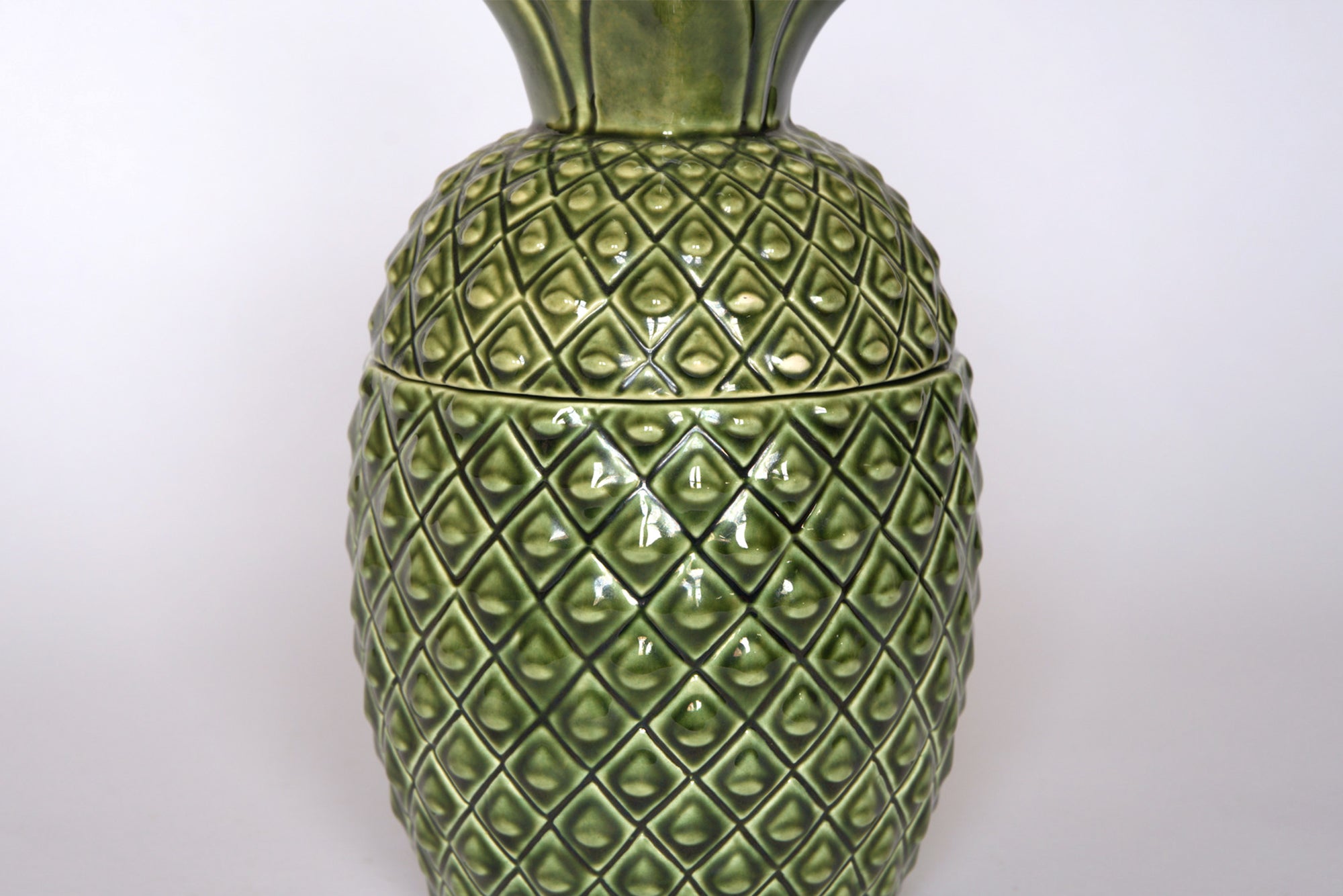 The Vintage Green Ceramic Pineapple Lidded Canister by Euro Trash features a diamond-textured surface and green glaze, making it perfect for adding tropical style to your kitchen. Displayed on a plain white background.