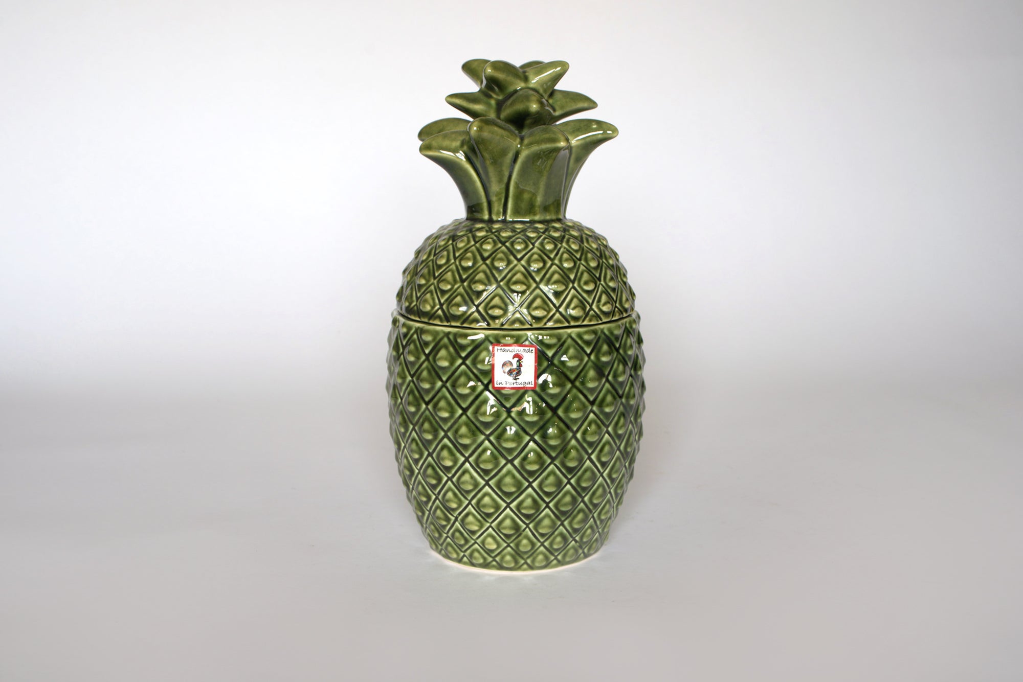 The Euro Trash Vintage Green Ceramic Pineapple Lidded Canister features a textured diamond pattern, leafy top, and small front label, making it a charming tropical decor piece for your kitchen.