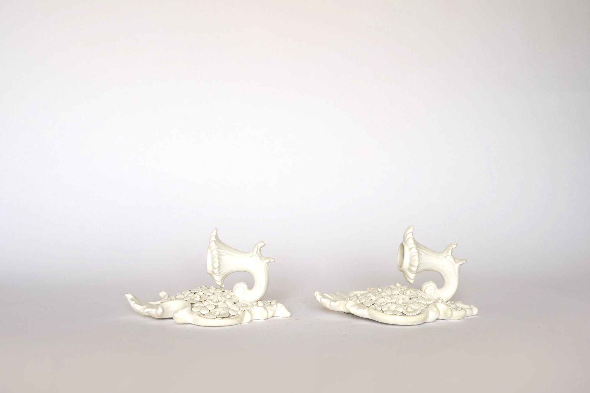 A pair of Euro Trash porcelain floral wall pocket vases are displayed side by side on a neutral surface against a pale, plain background.