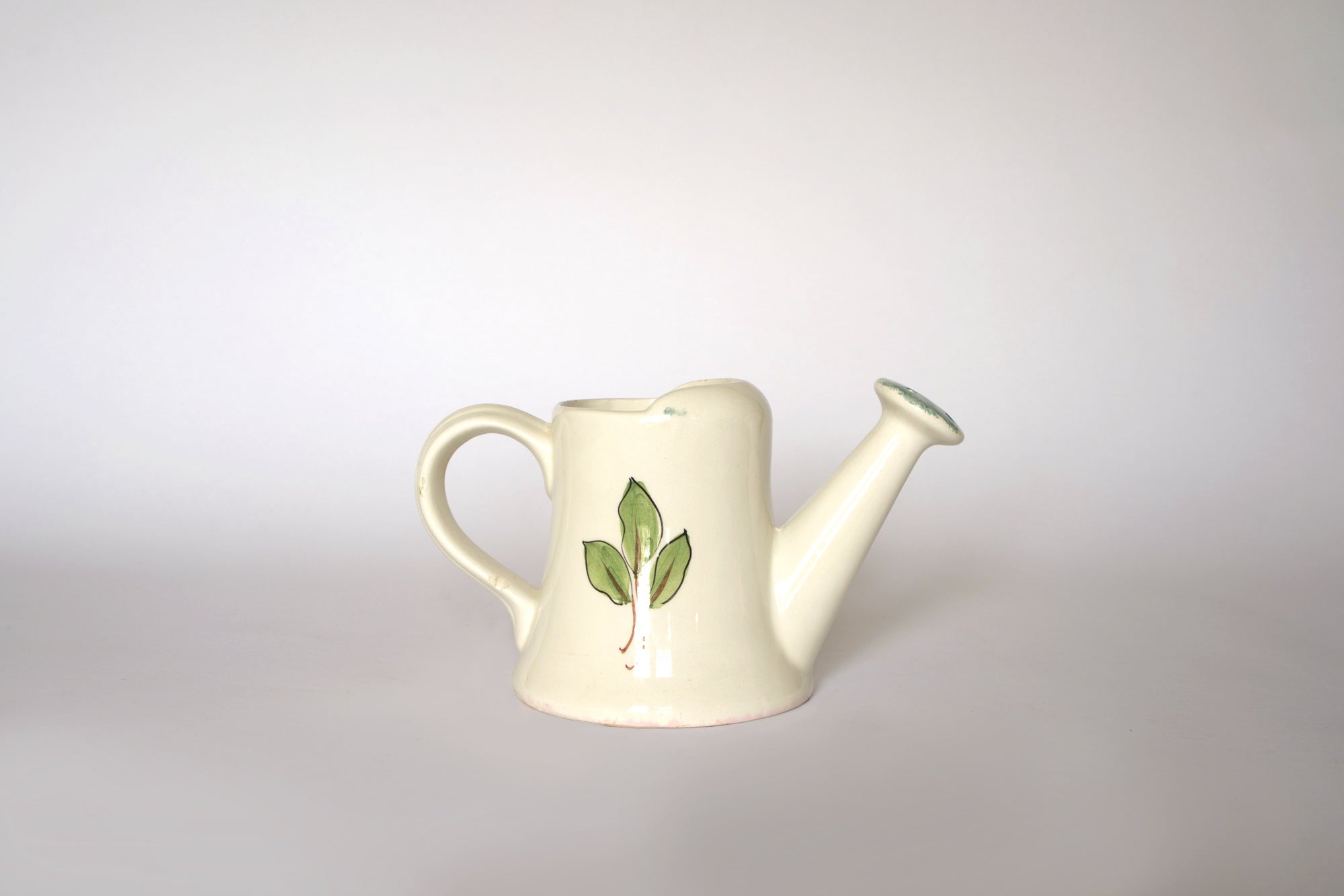 The Euro Trash Vintage Hand-Painted Floral Ceramic Watering Can features a curved handle and spout with a floral design, displayed against a plain light background.