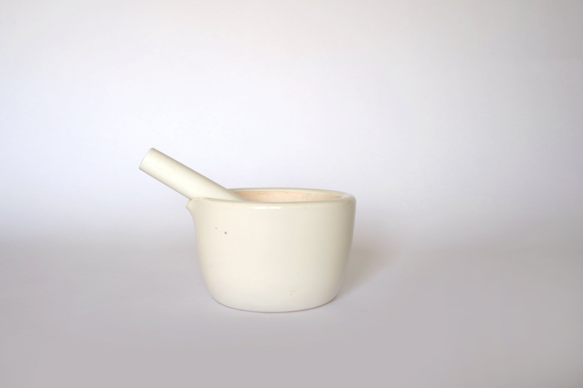 The Euro Trash Vintage White Ceramic Mortar and Pestle Set adds a decorative touch to kitchenware, shown on a plain white surface with a light background.