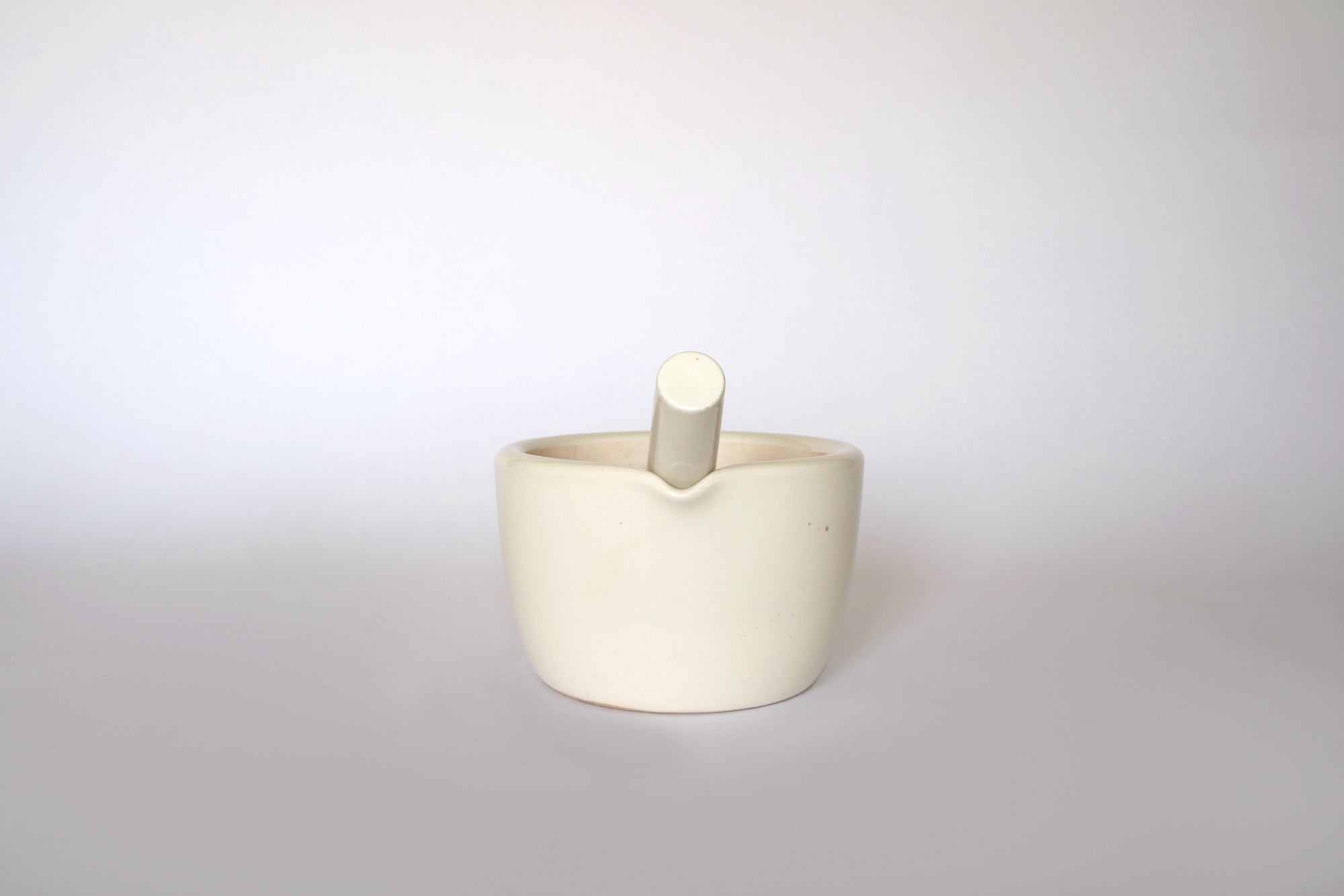 The Euro Trash Vintage White Ceramic Mortar and Pestle Set features a classic white bowl with the pestle resting inside, displayed on a plain white background—an elegant addition to any kitchen decor.