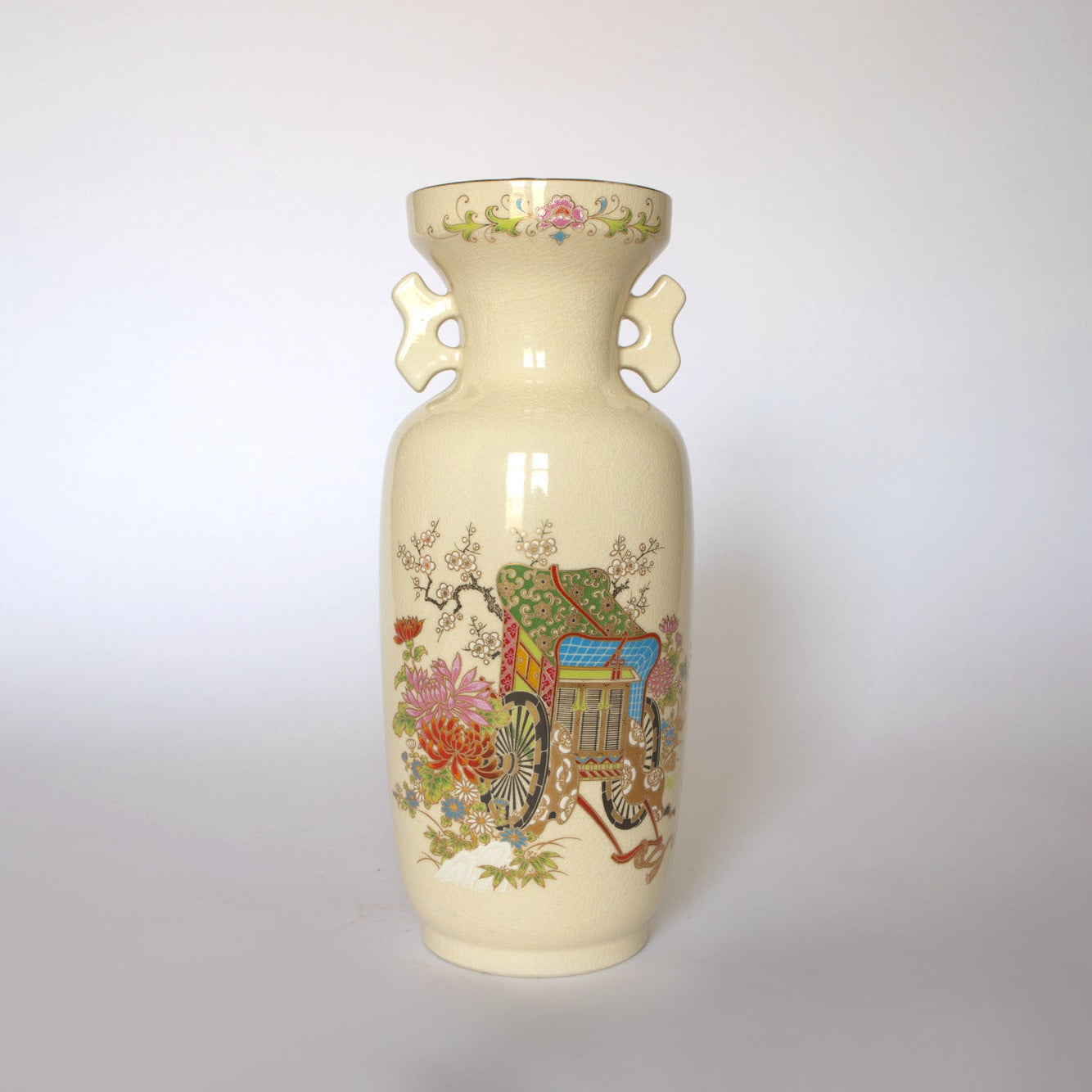 The Euro Trash Vintage Japanese Satsuma Style Ceramic Vase features cream-colored ceramic, ornate handles, and colorful floral and garden scenes with a traditional East Asian house on a plain background.