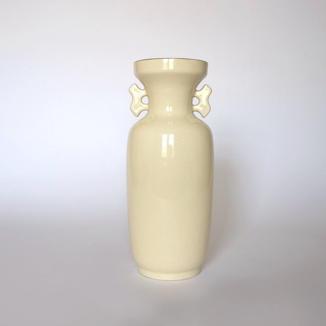 The Euro Trash Vintage Japanese Satsuma Style Ceramic Vase features a tall, cream-colored glossy finish with two decorative handles, making it a striking statement piece against a plain white background.