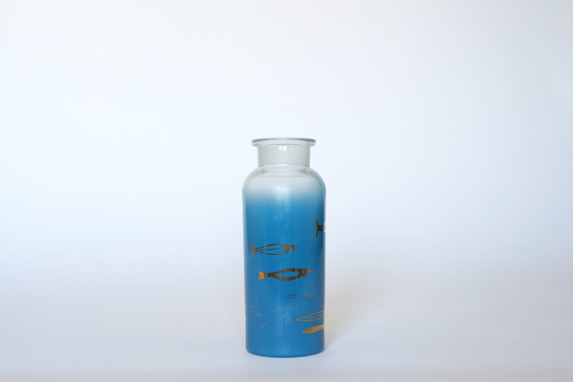 The Euro Trash Vintage Blue Frosted Glass Vase features gold and black fish near the base; gold fish motifs stand out against the vase’s blue frosted finish.
