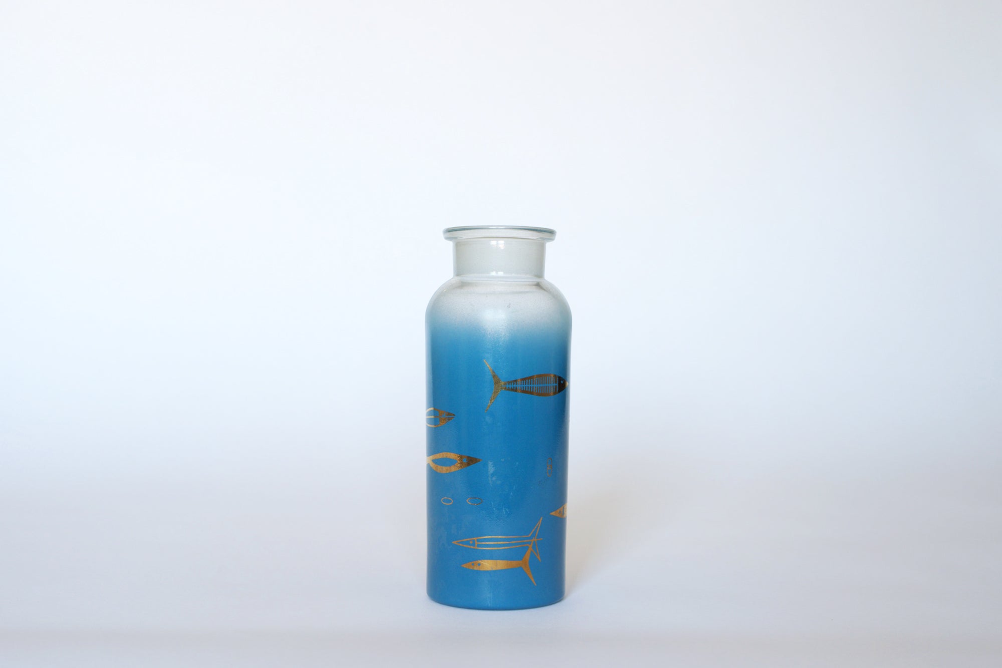 The Euro Trash Vintage Blue Frosted Glass Vase, featuring gold fish designs, stands tall and upright against a plain white background.
