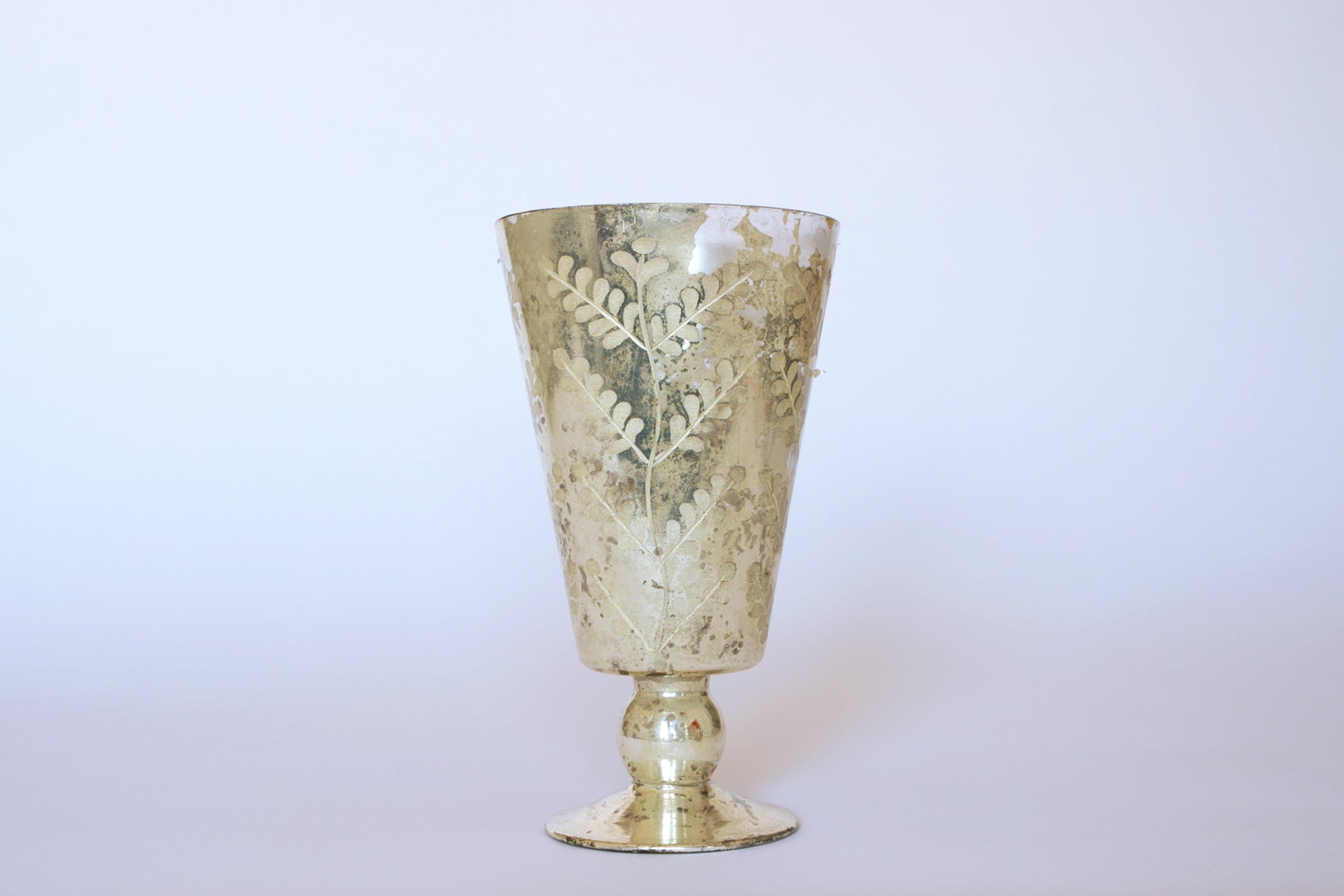 The Euro Trash Vintage Mercury Glass Vase features a flared rim, etched leaf and branch patterns, and stands on a simple round base, displayed against a plain light background.