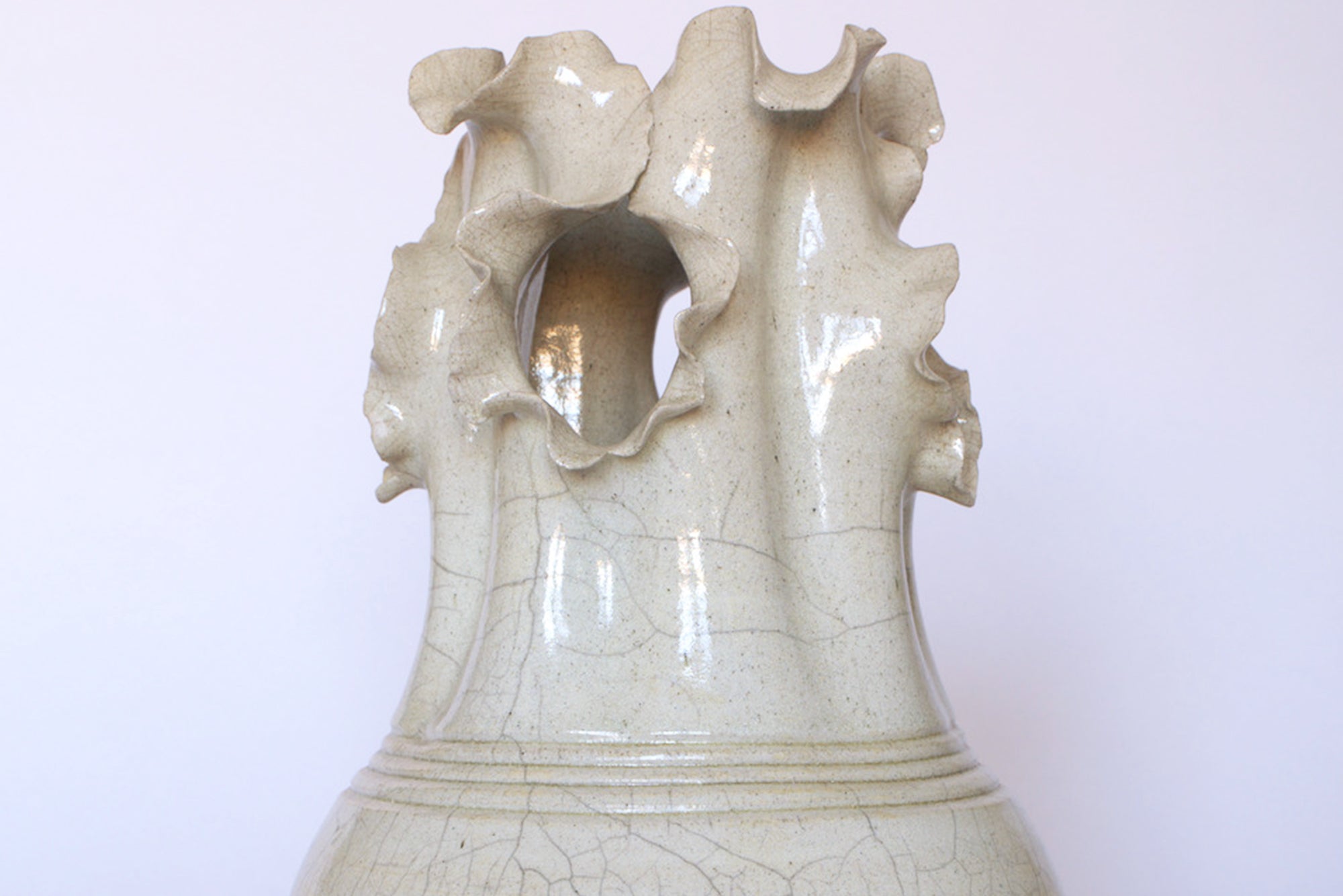 A close-up of the Vintage Two-Tone Glaze Vase with Ruffled Rim by Euro Trash, highlighting its sculptural form and unique ruffled edge against a plain light background.