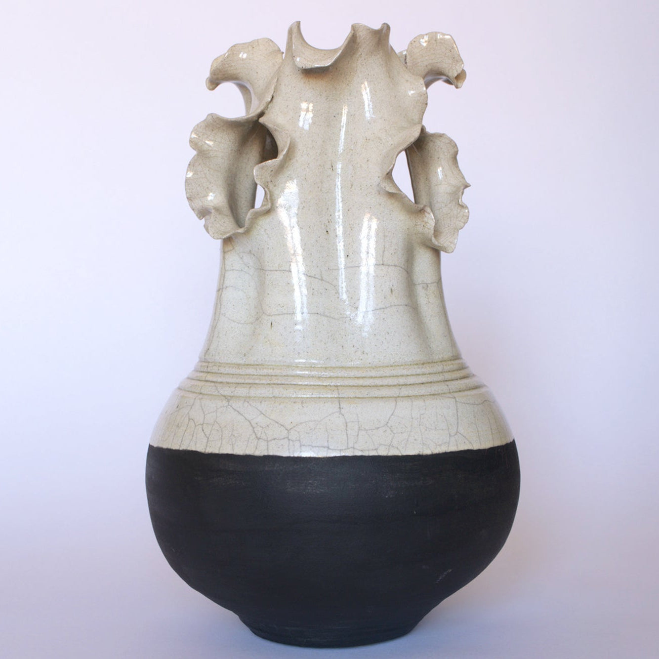 The Vintage Two-Tone Glaze Vase with Ruffled Rim by Euro Trash features a glossy crackle cream upper half, matte black lower section, and dramatic wavy ruffled edges at the neck. Photographed against a plain white background.
