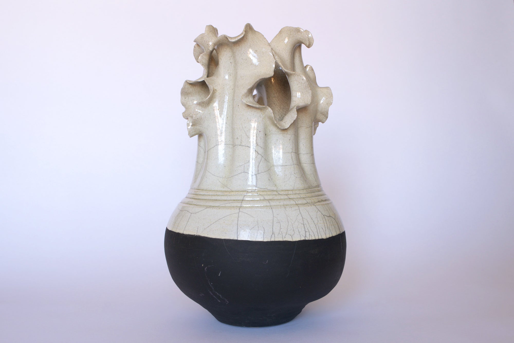 The Euro Trash Vintage Two-Tone Glaze Vase with Ruffled Rim features a rounded black base, a white upper section, and an irregular sculpted rim evoking organic shapes against a plain background.