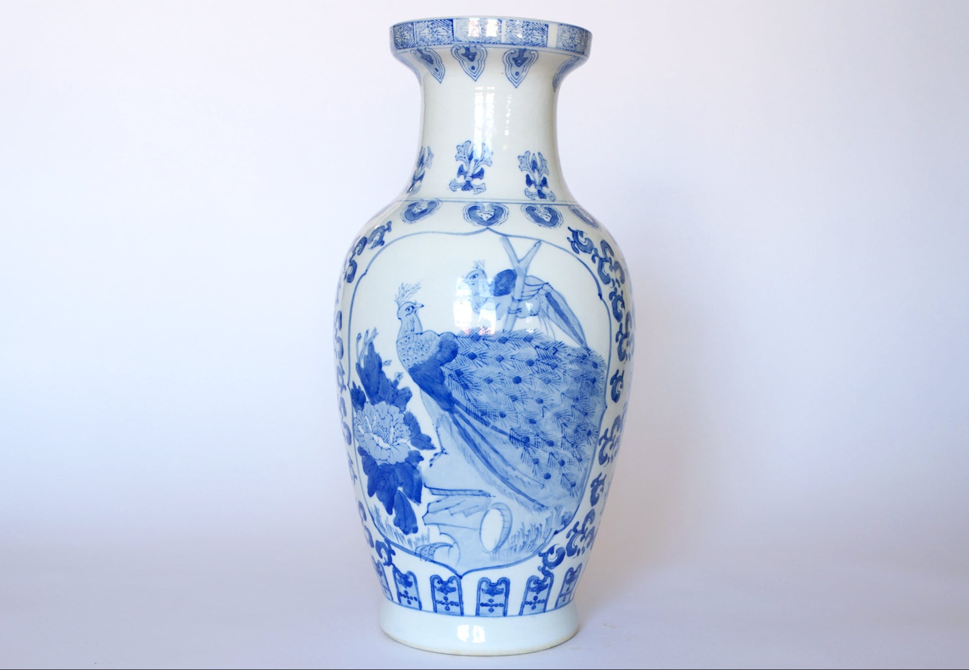 The Vintage Blue & White Porcelain Peacock Vase by Euro Trash features detailed floral motifs and a graceful peacock, hand-painted on classic Asian porcelain against a light background.
