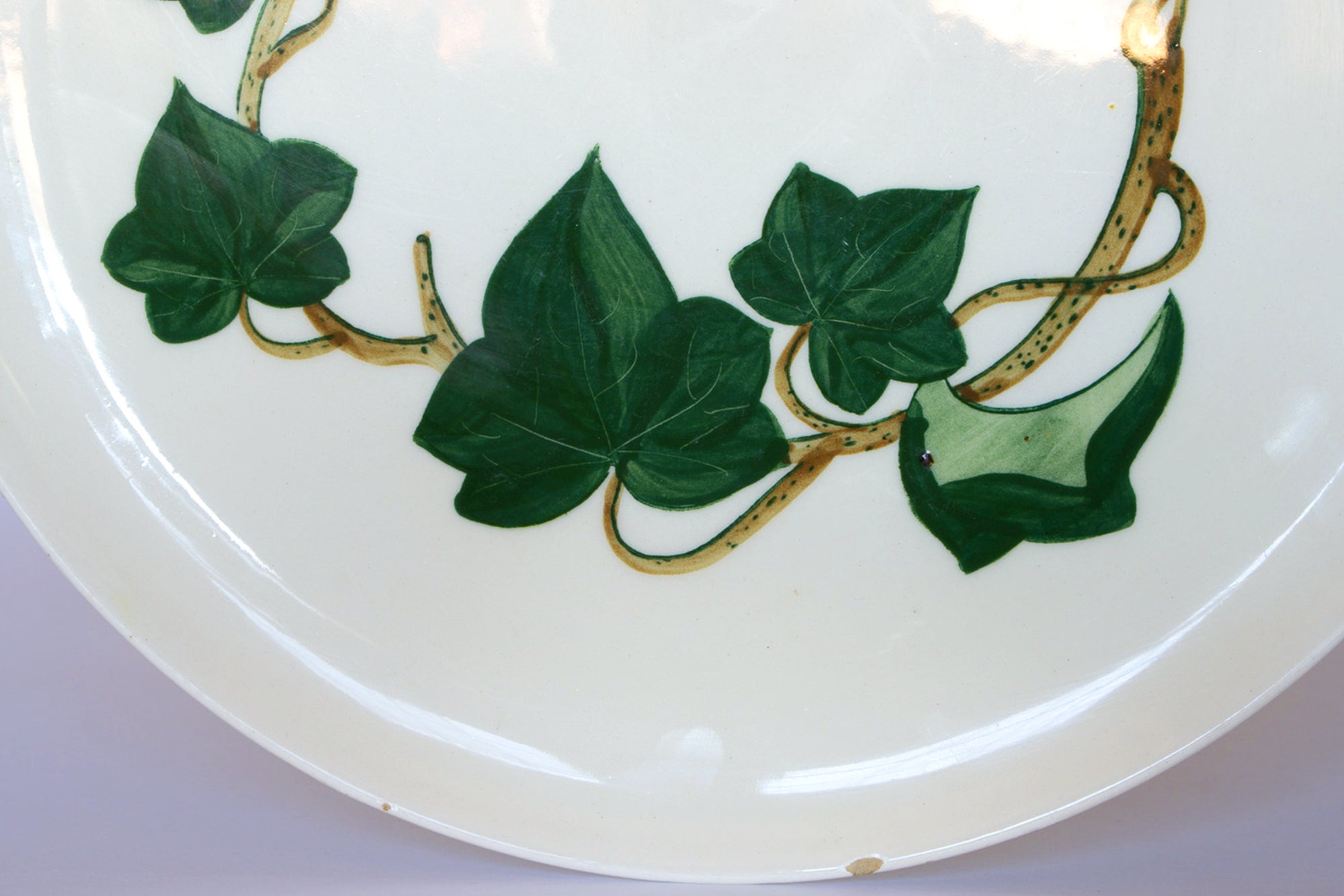 The Euro Trash Vintage Ivory Ceramic Bowl with Ivy Leaf features hand-painted green ivy and yellow vines on white, making it an ideal decorative centerpiece.