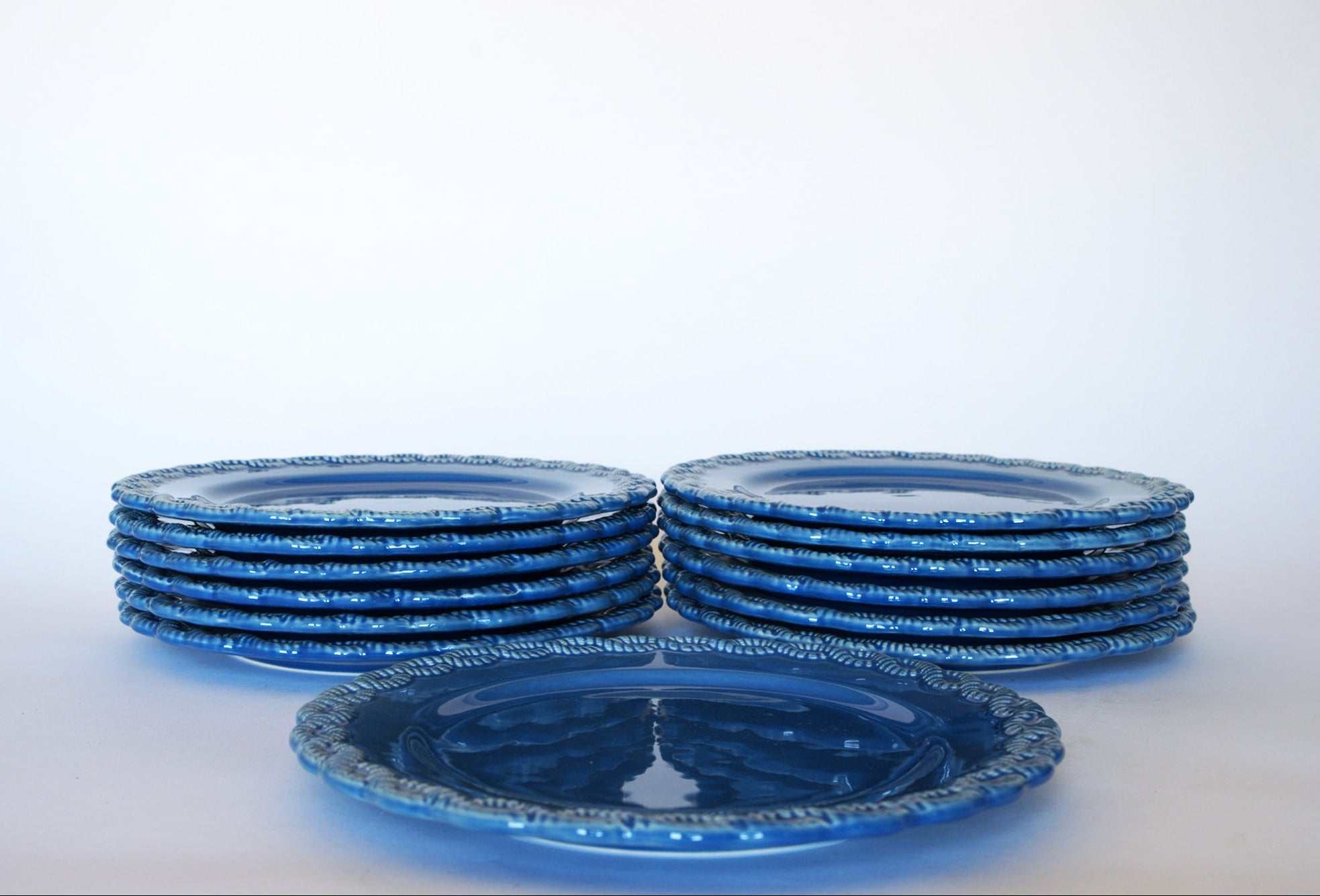 Ten Euro Trash Vintage Blue Rim Dinner Plates with Beaded Edge are stacked in two piles, plus one plate displayed in front. The textured beaded rims and classic blue-and-white design stand out against a plain white background.