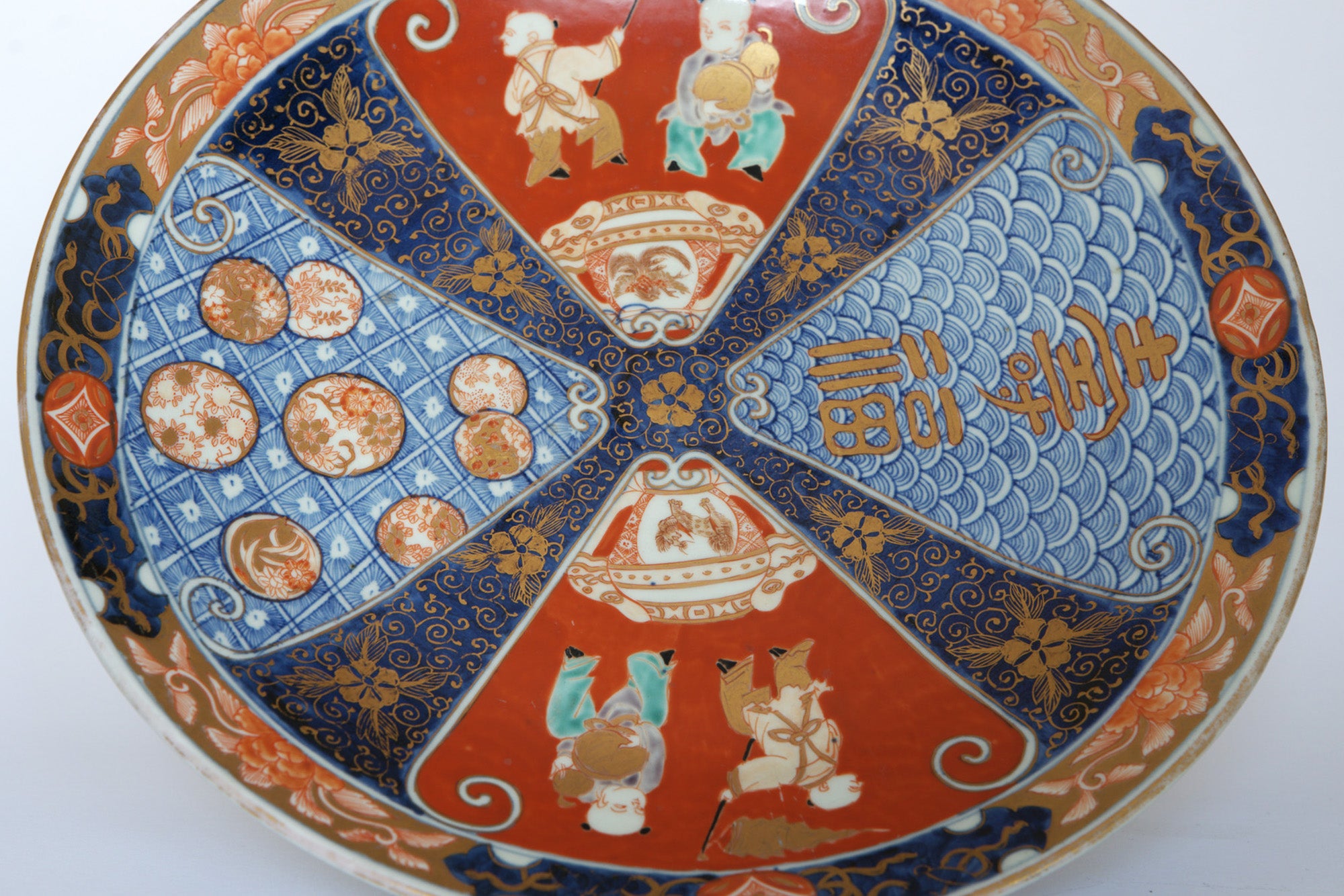 The Euro Trash Vintage Imari Style Porcelain Decorative Plate showcases intricate red, blue, and gold patterns with figures, geometric designs, and stylized Asian symbols—perfect as a striking decorative wall piece.