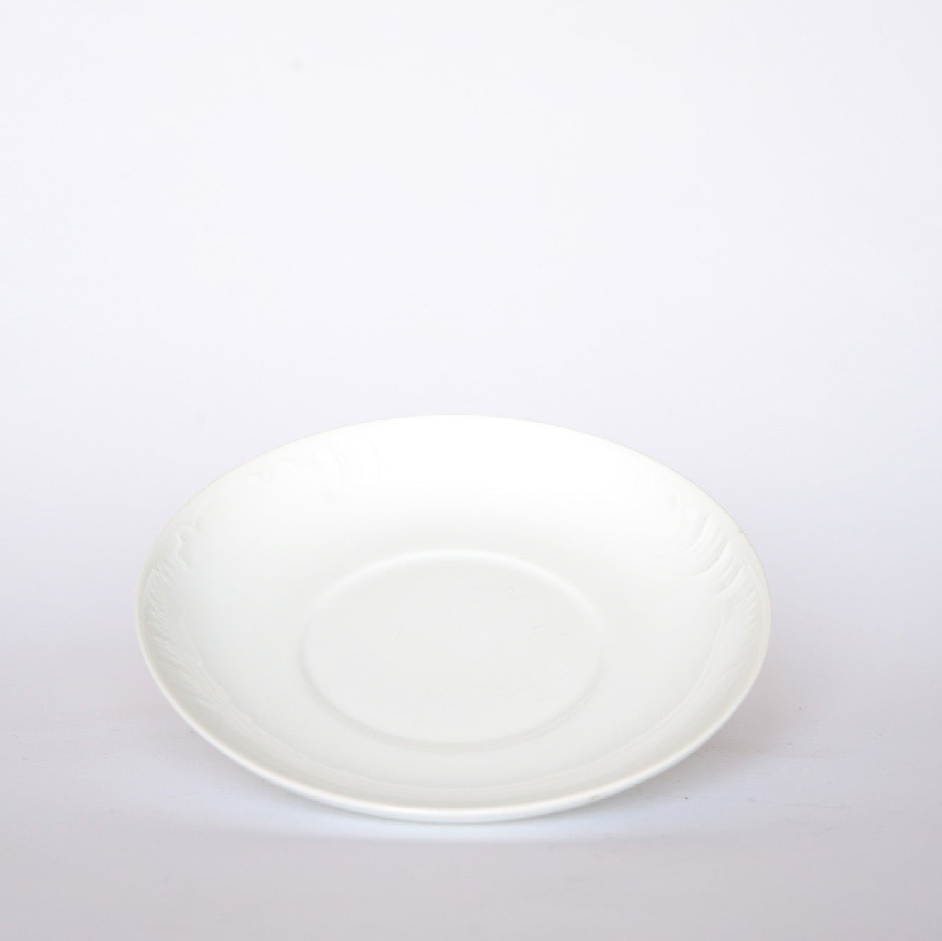 The Euro Trash Vintage White Embossed Rim Ceramic Bowl is centered on a white background, featuring a smooth surface, a slight central depression, and subtle embossed ridges along the rim.