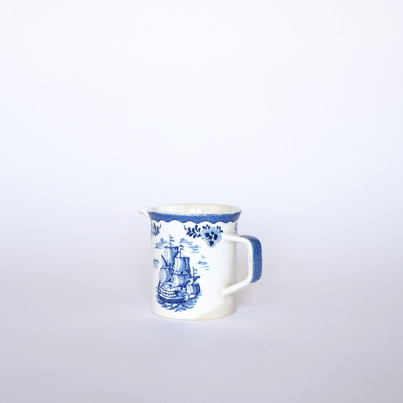 The Euro Trash Vintage Blue & White Ship Motif Porcelain Creamer features intricate blue patterns and a nautical ship design, displayed against a plain white background.
