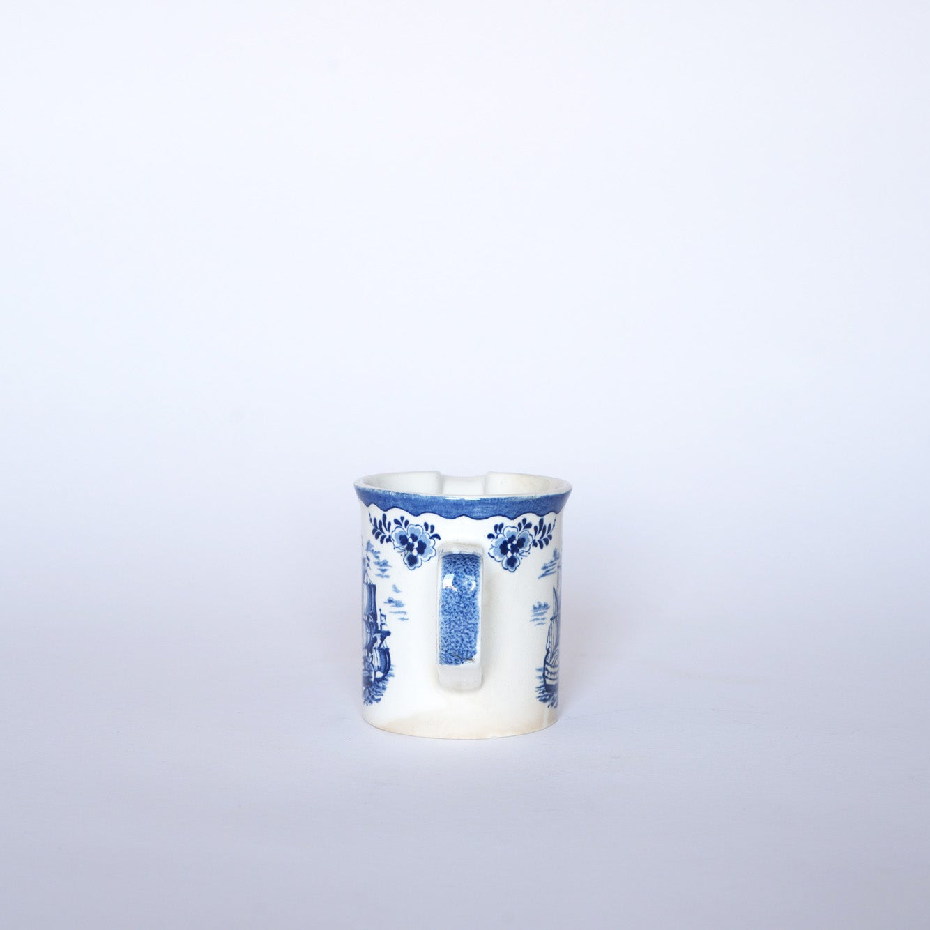 The Euro Trash Vintage Blue & White Ship Motif Porcelain Creamer, featuring a rectangular handle and scenic blue patterns, is showcased against a plain white background.
