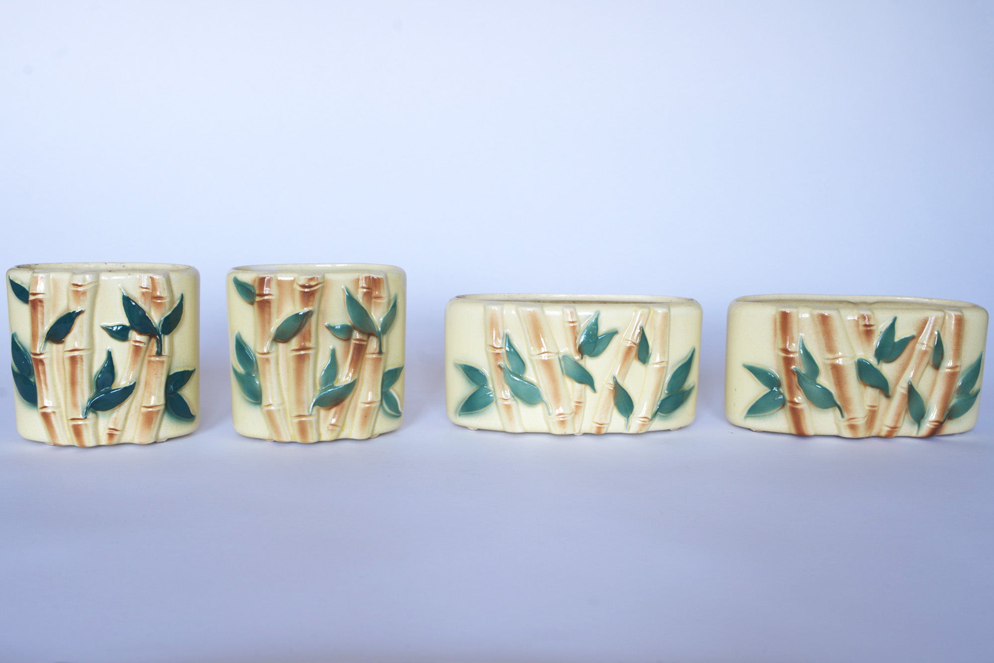 Four Vintage Bamboo Ceramic Vases by Euro Trash, featuring a bamboo motif and green leaf design, are arranged in a row against a plain light background—ideal for adding nature-inspired style to your decor.