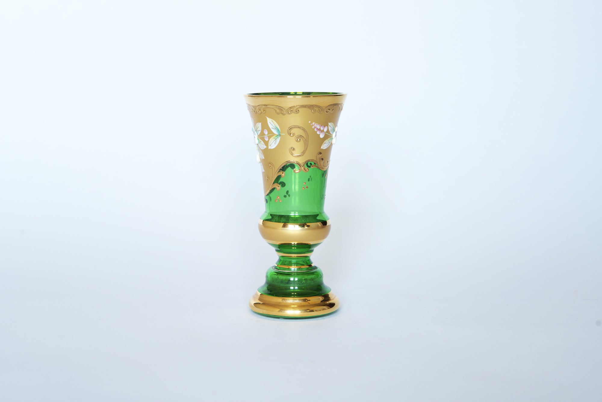 The Euro Trash Vintage Green & Gold Hand-Painted Floral Glass Vase features ornate gold patterns and white floral designs on emerald glass, reminiscent of a vintage goblet, and is displayed on a plain white background.