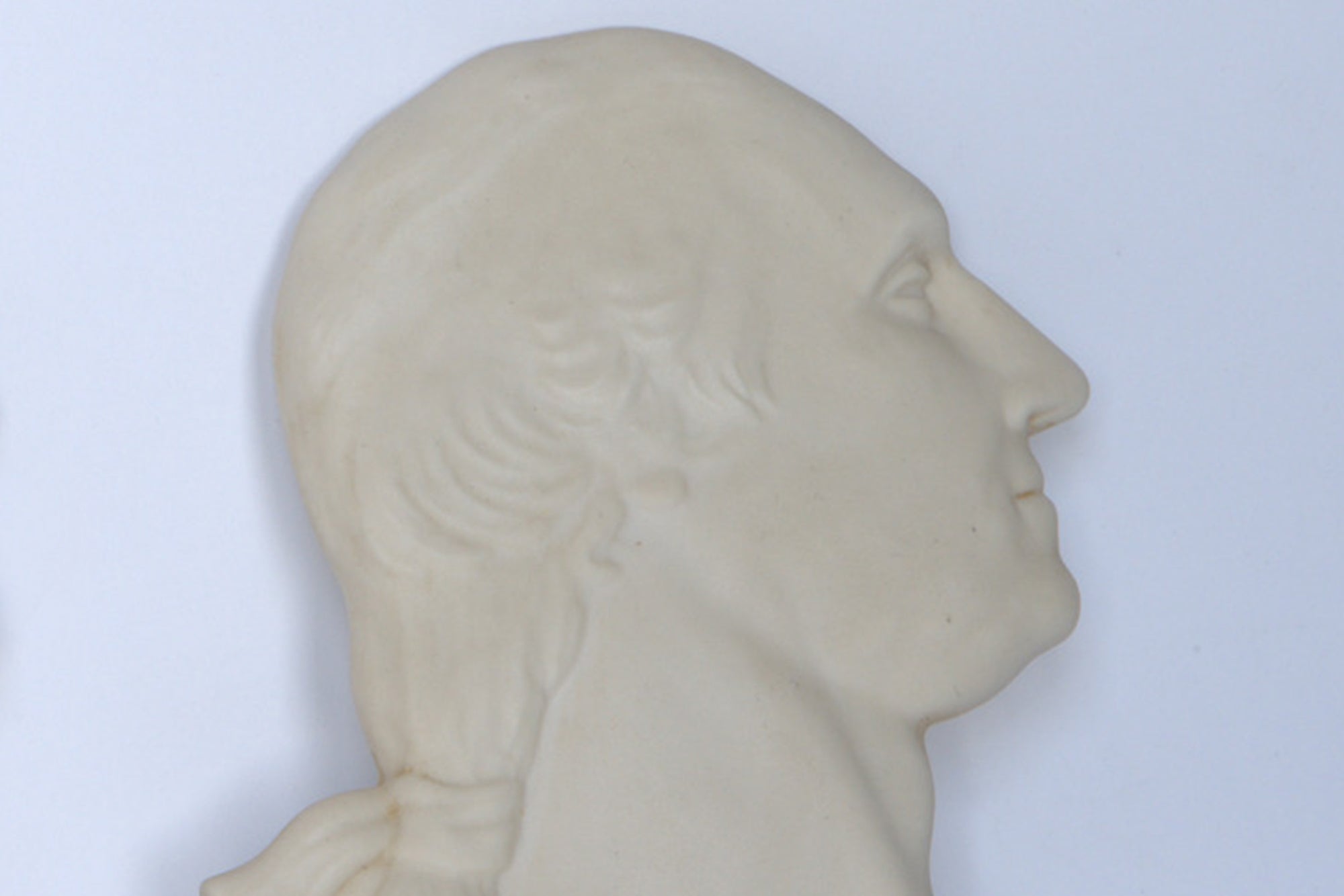 The Euro Trash Vintage White Classical Bust Wall Plaques feature a side profile relief of a man's head and upper neck, carved in white material with short hair tied back, evoking classical elegance against a plain light background.