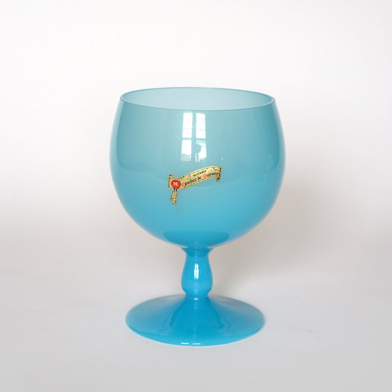 The Vintage Blue Opaline Murano Glass Goblet by Euro Trash features a large, round design with a short stem and a gold and red label, displayed against a plain white background—a standout collectible art glass piece.