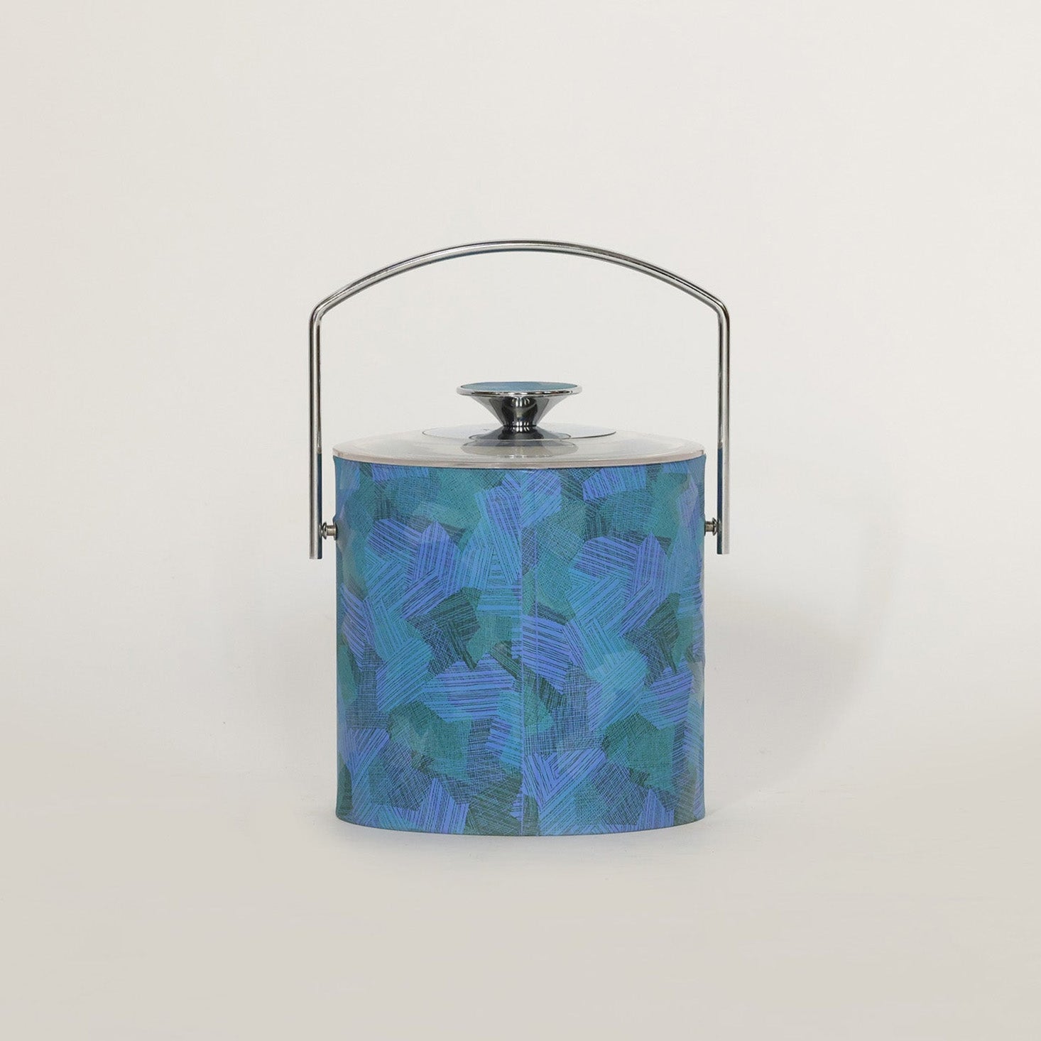The Euro Trash Annie Mid Century Blue Lucite Ice Bucket features a cylindrical shape, abstract blue and teal pattern, shiny metal lid, and curved handle, adding a pop of color to modern decor against a white background.