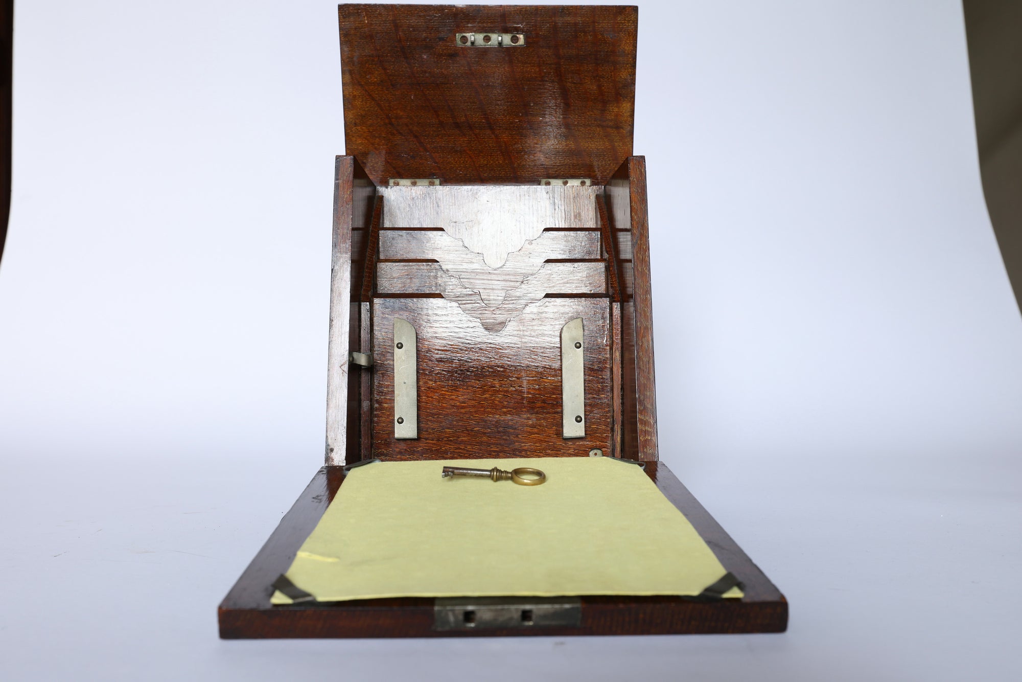 The Euro Trash Antique Inlaid Wooden Document Box has a hinged lid, metal brackets, and interior slots. A metal key lies on yellow paper inside this decorative storage box, all set against a plain white background.