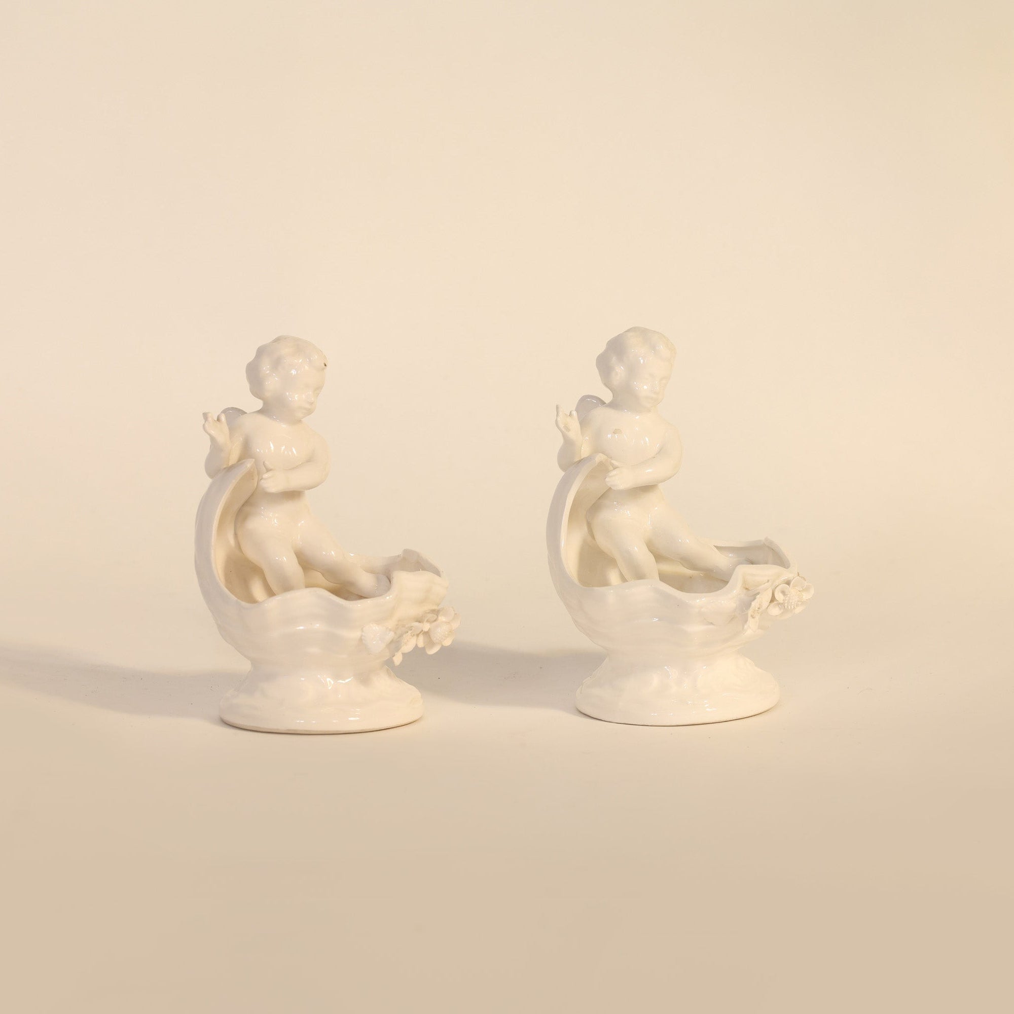 Two white ceramic figures on a beige background