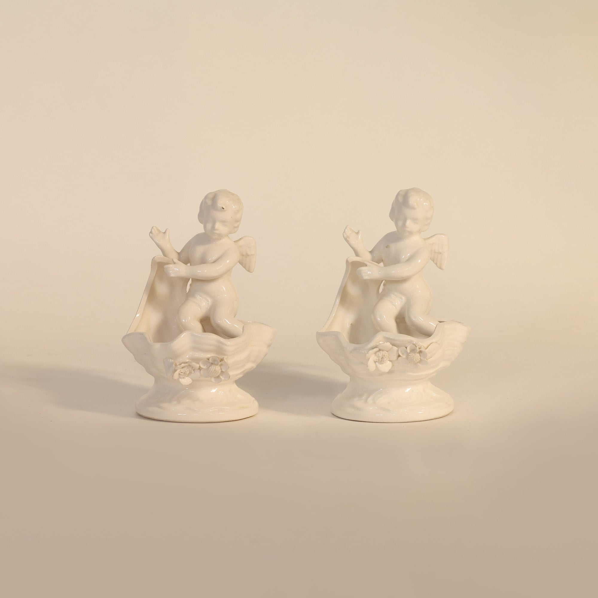 Two white ceramic statues on a beige background
