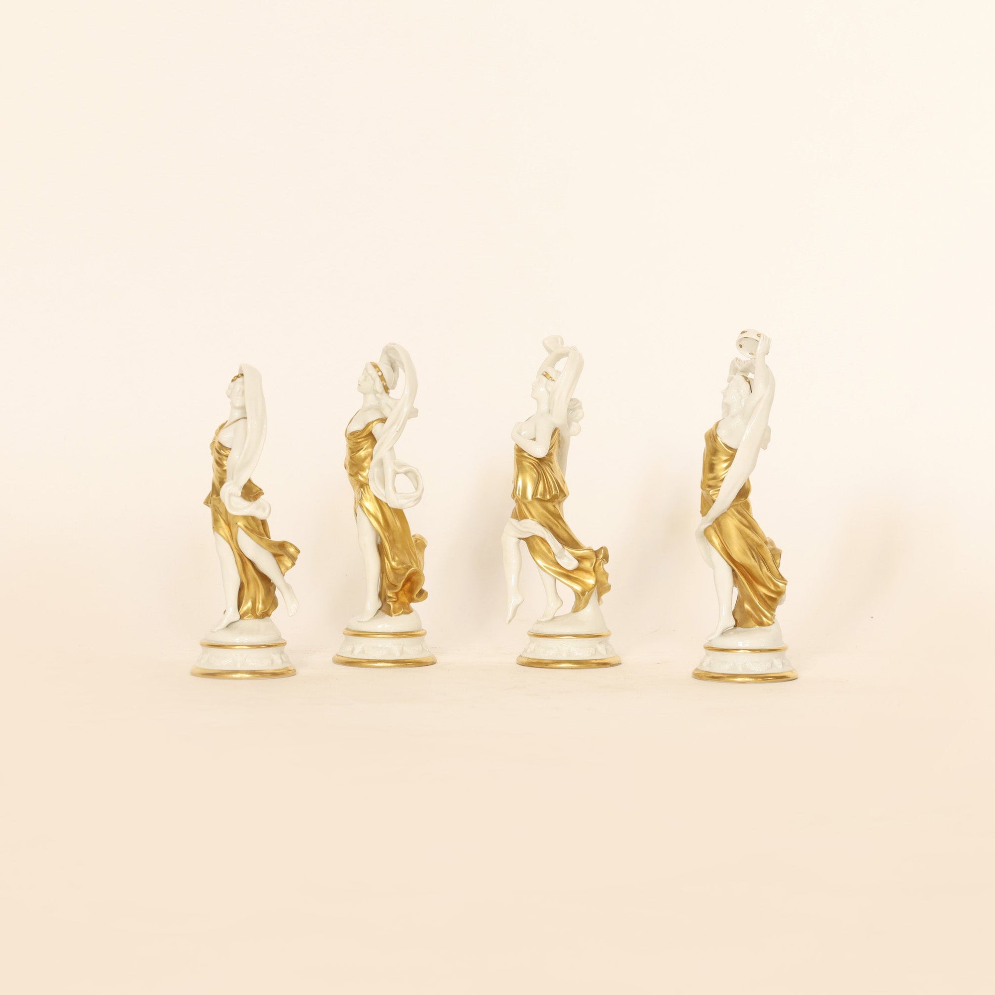 four figural sculptures on a beige background