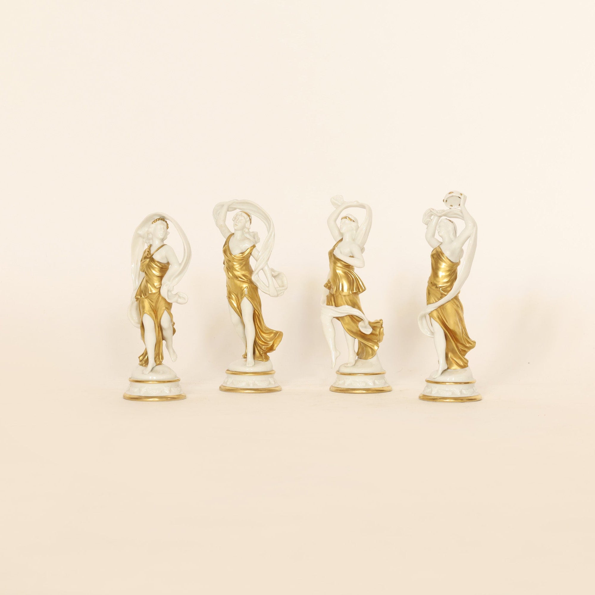 four figural sculptures on a beige background