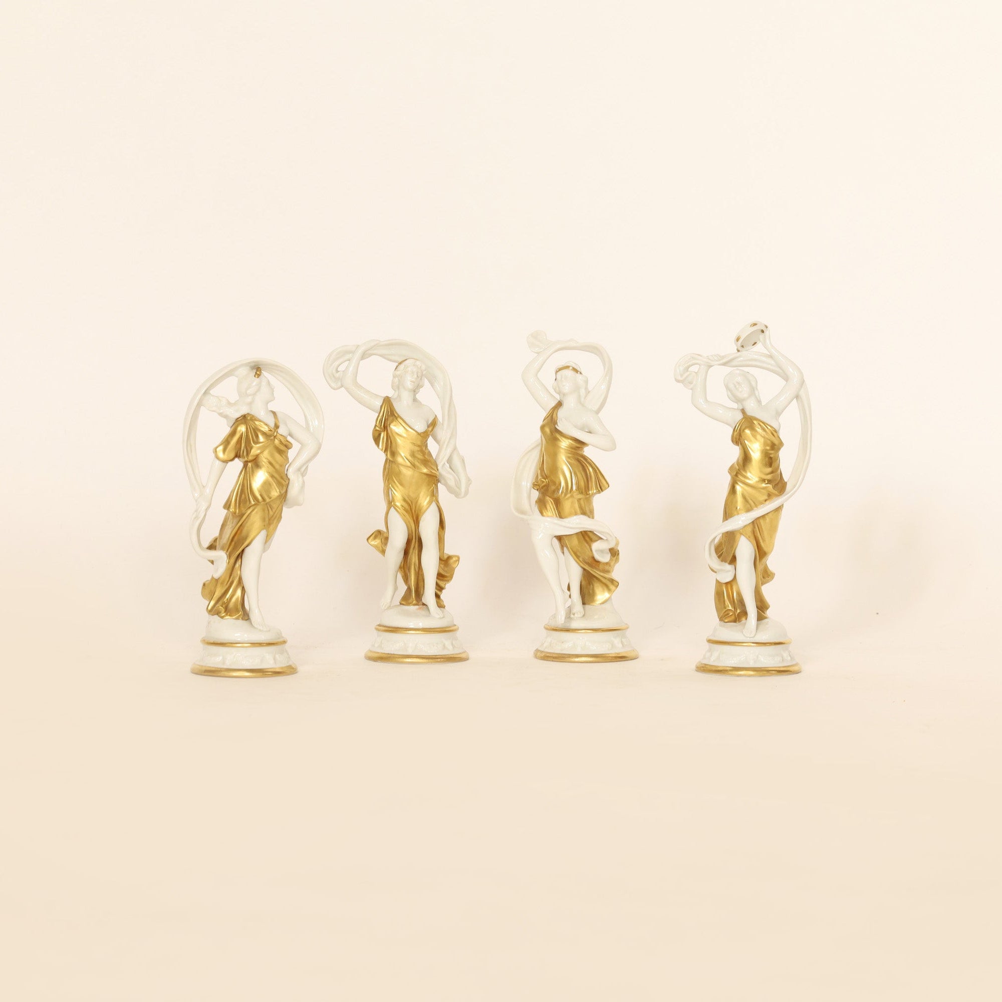 four figural sculptures on a beige background