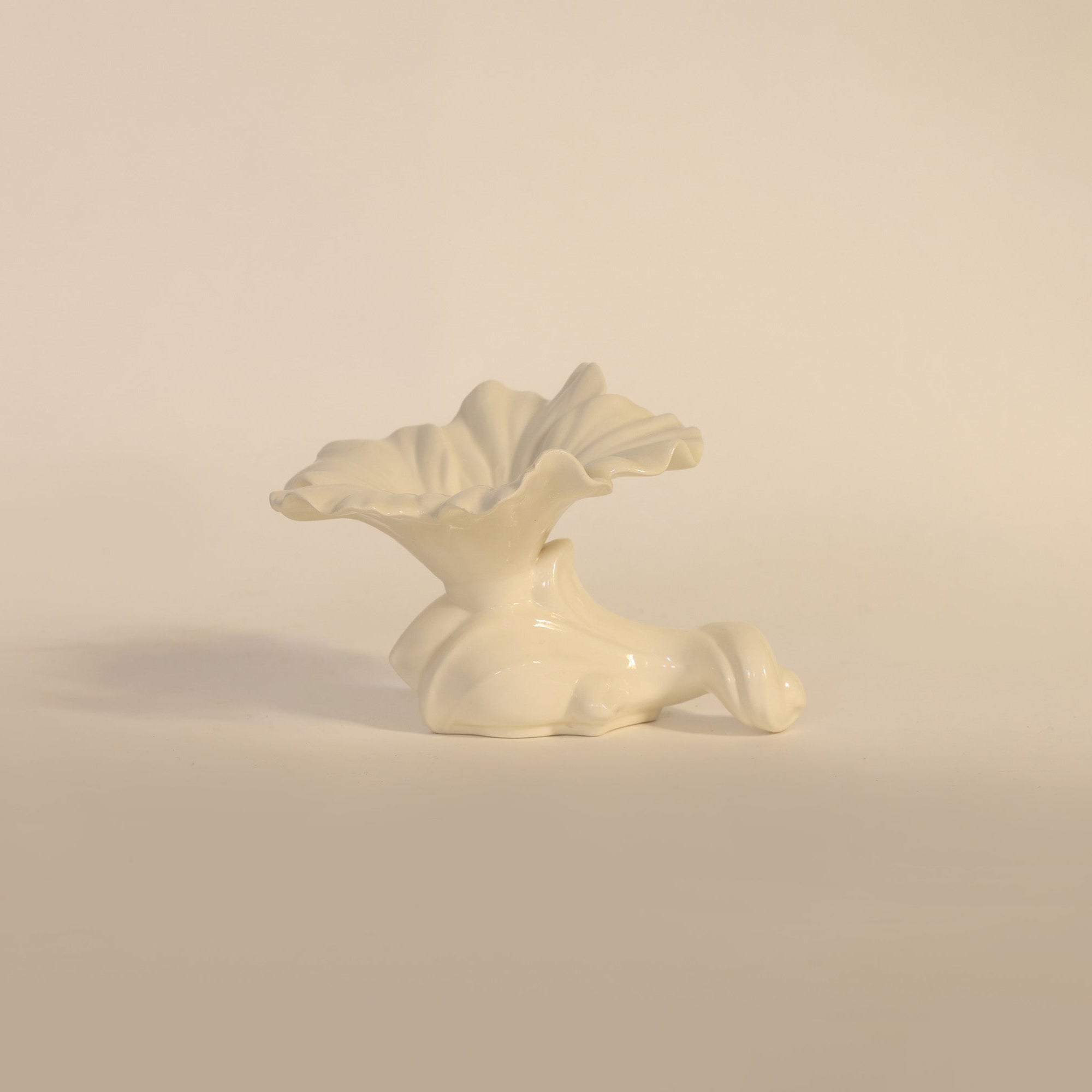 White ceramic sculpture of a flower on a beige background