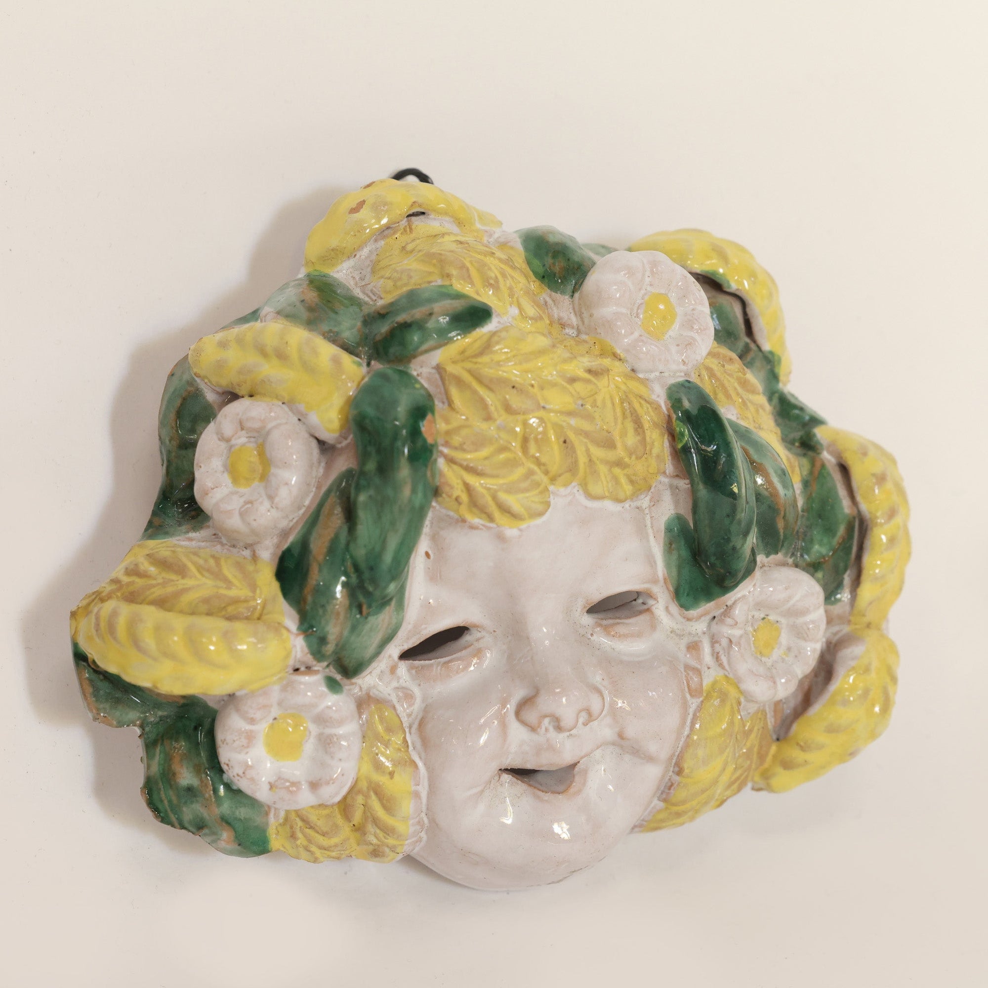 Decorative wall mask with floral design on a plain background