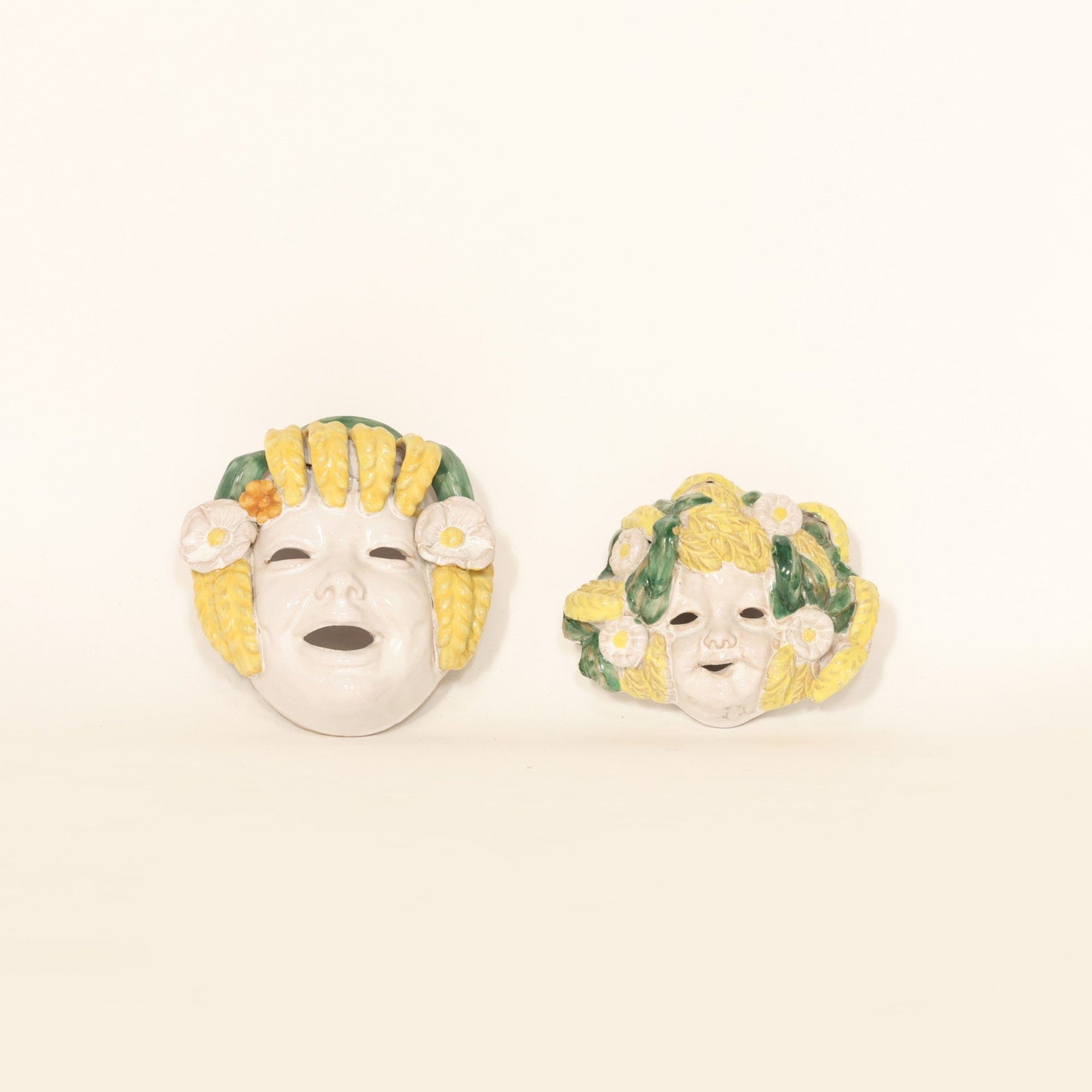 pair of Italian majolica wall masks on beige background