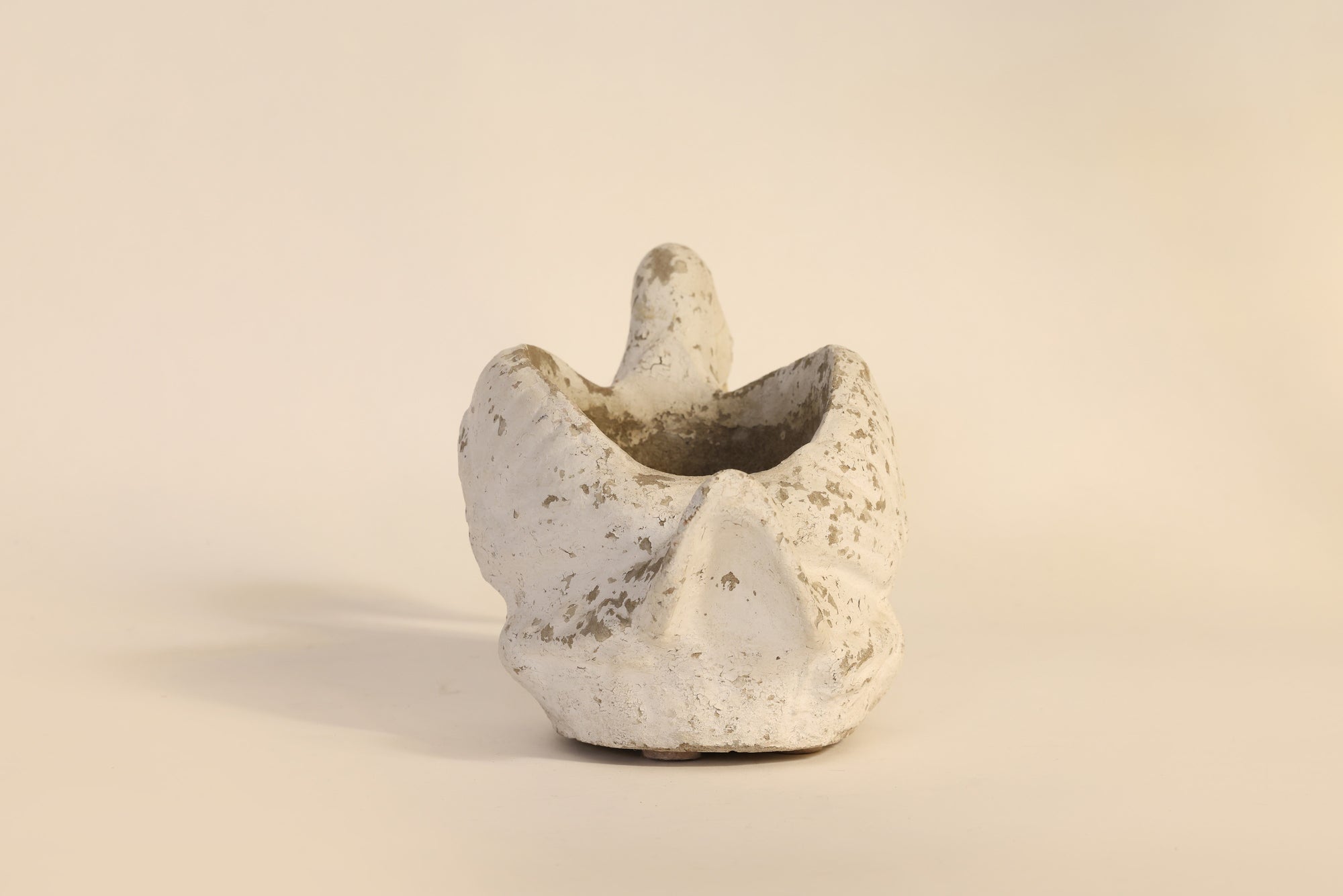 Small ceramic vase with textured surface on a beige background