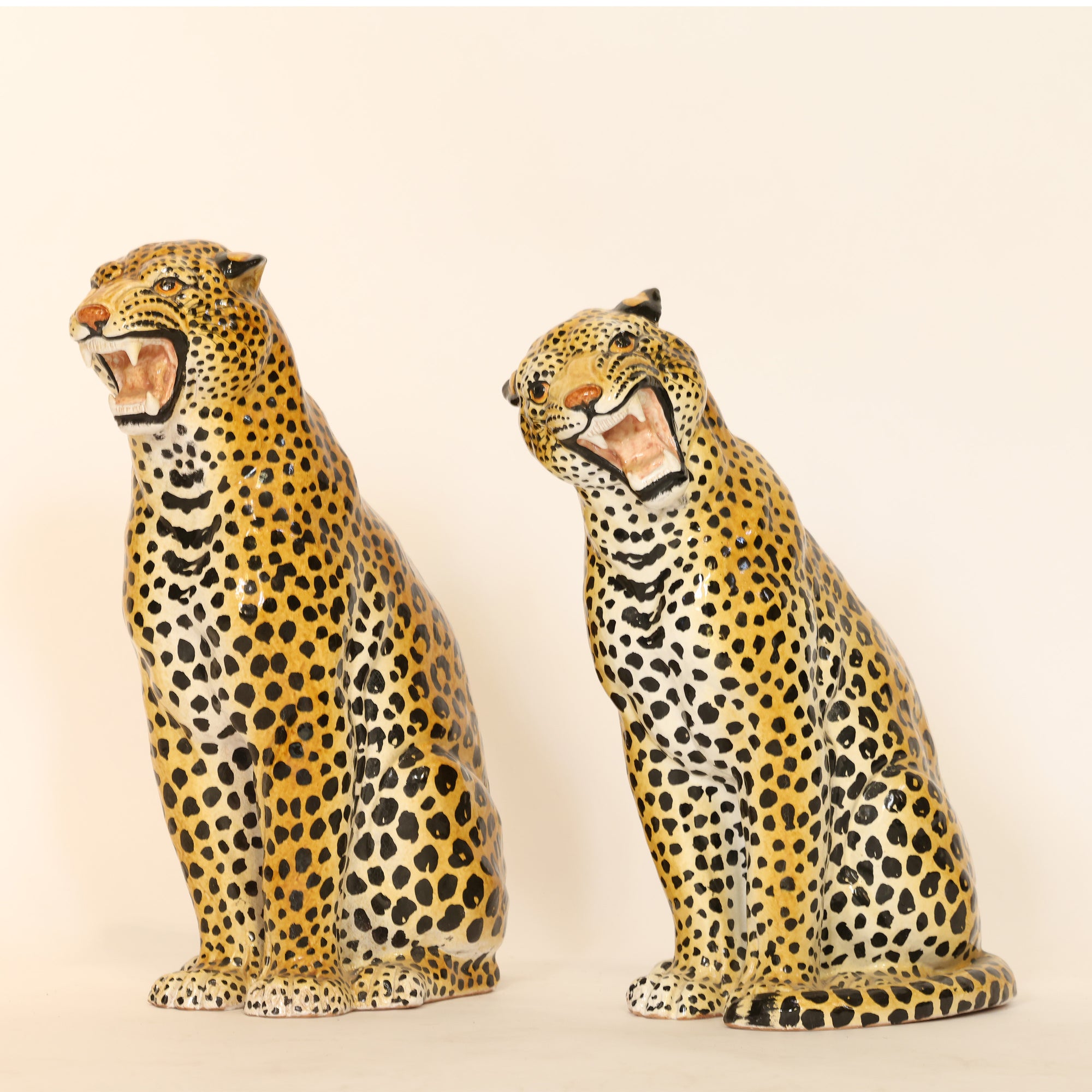 Two ceramic leopard figurines on a beige background